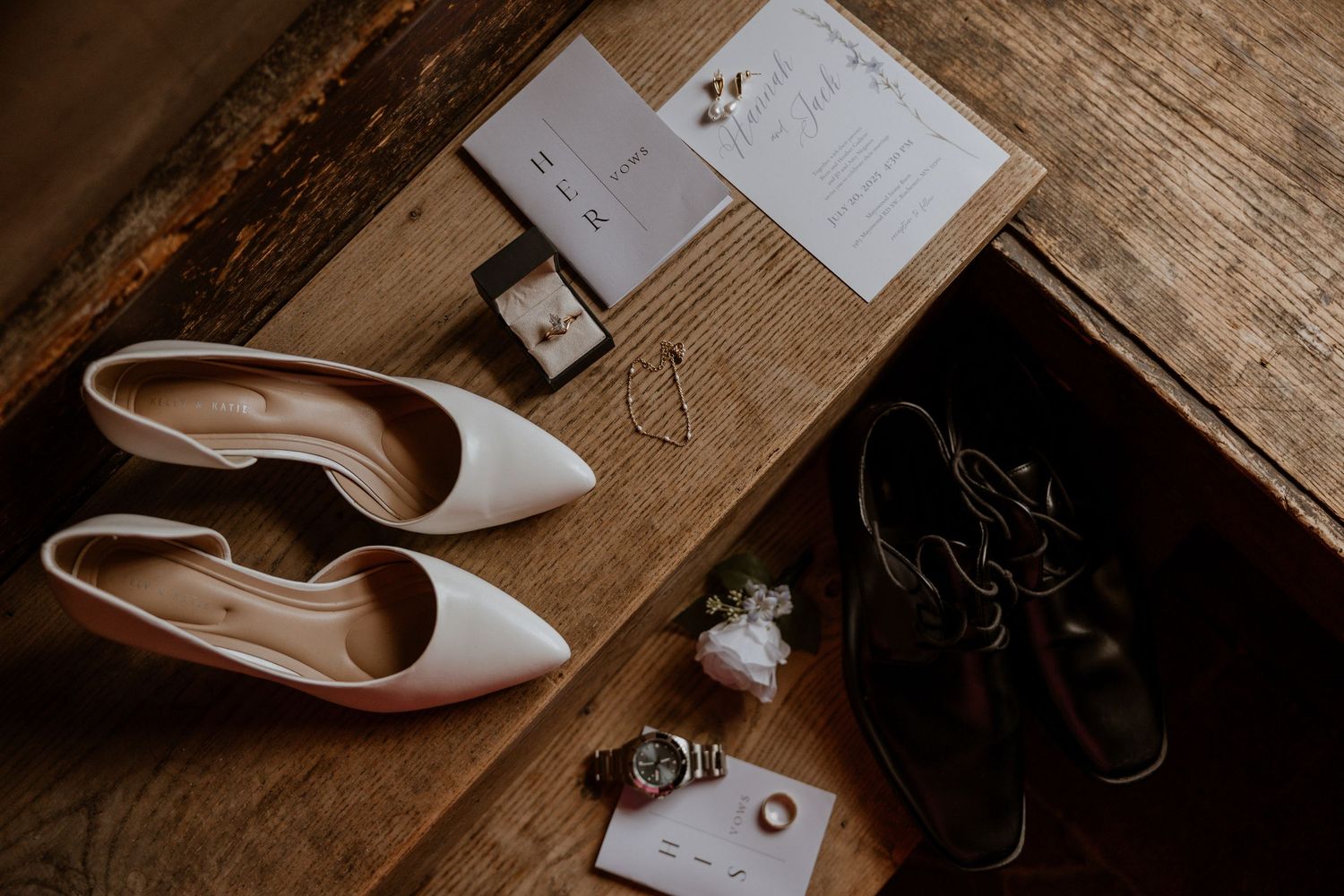 Wedding accessories and stationery arranged on rustic wooden surface.