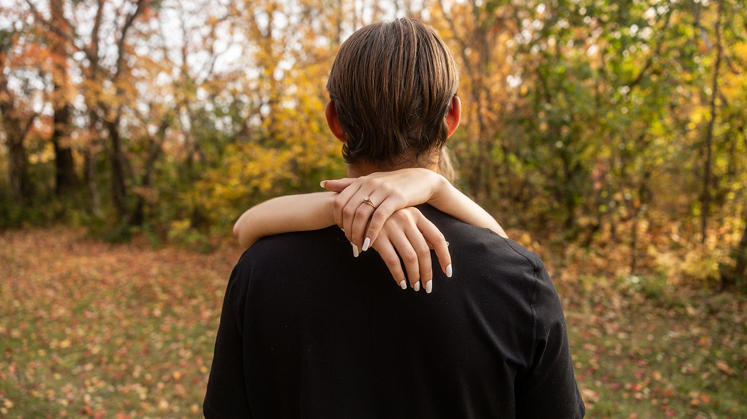 A romantic autumn photoshoot showing a couple embracing in nature.