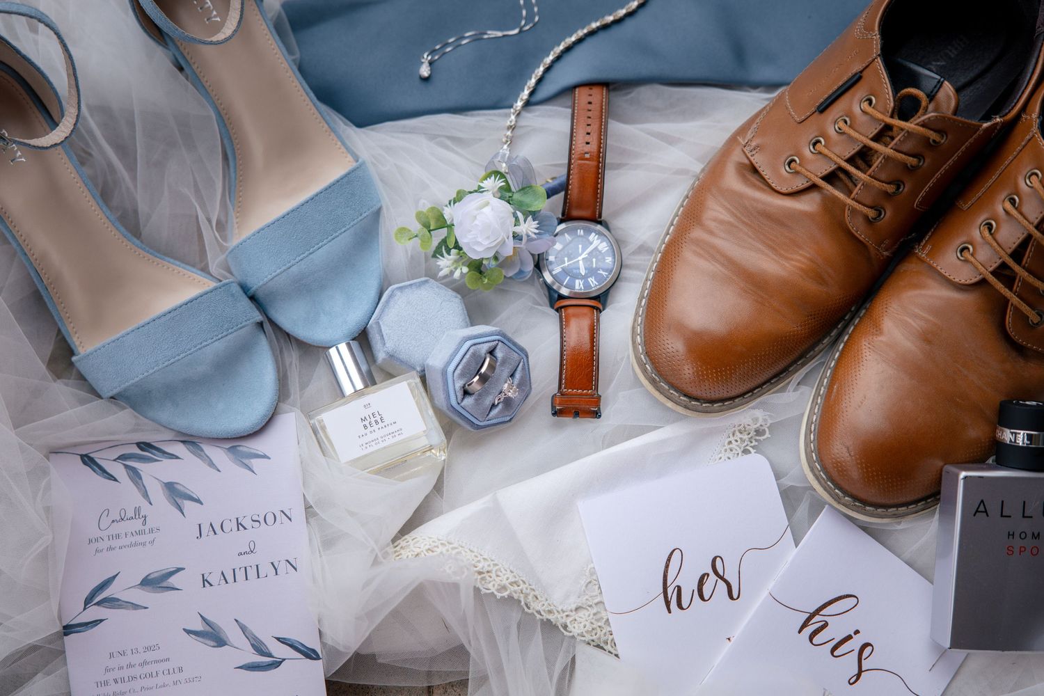 Brown leather dress shoes and wedding details arranged on white surface with blue accents.