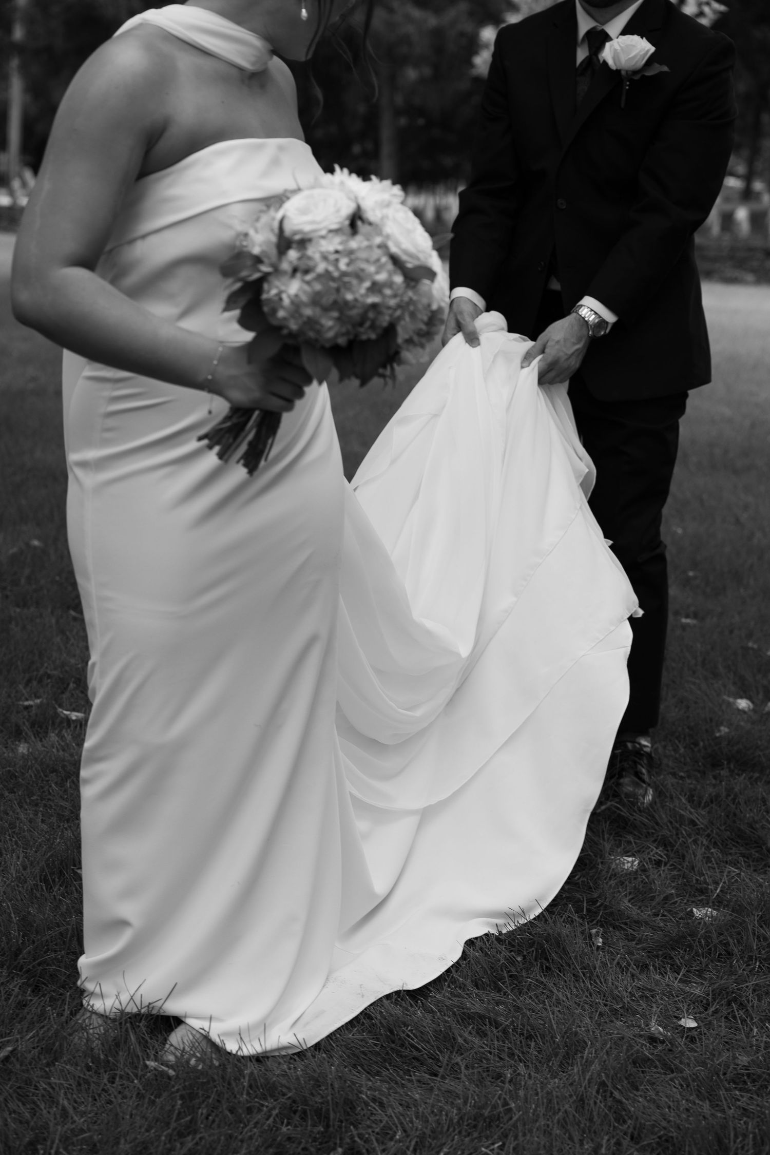 Black and white photo of wedding dress movement and details during outdoor celebration.
