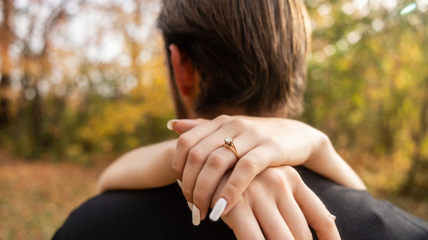 Close-up shot of a couple's tender moment in an autumn forest setting.