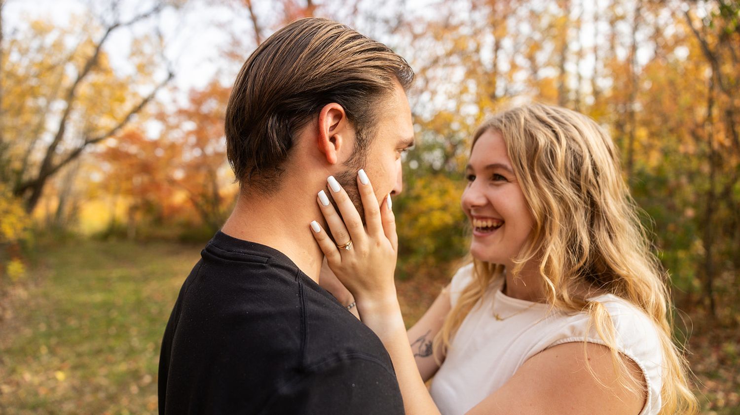 Two people share a romantic moment against a backdrop of fall colors.