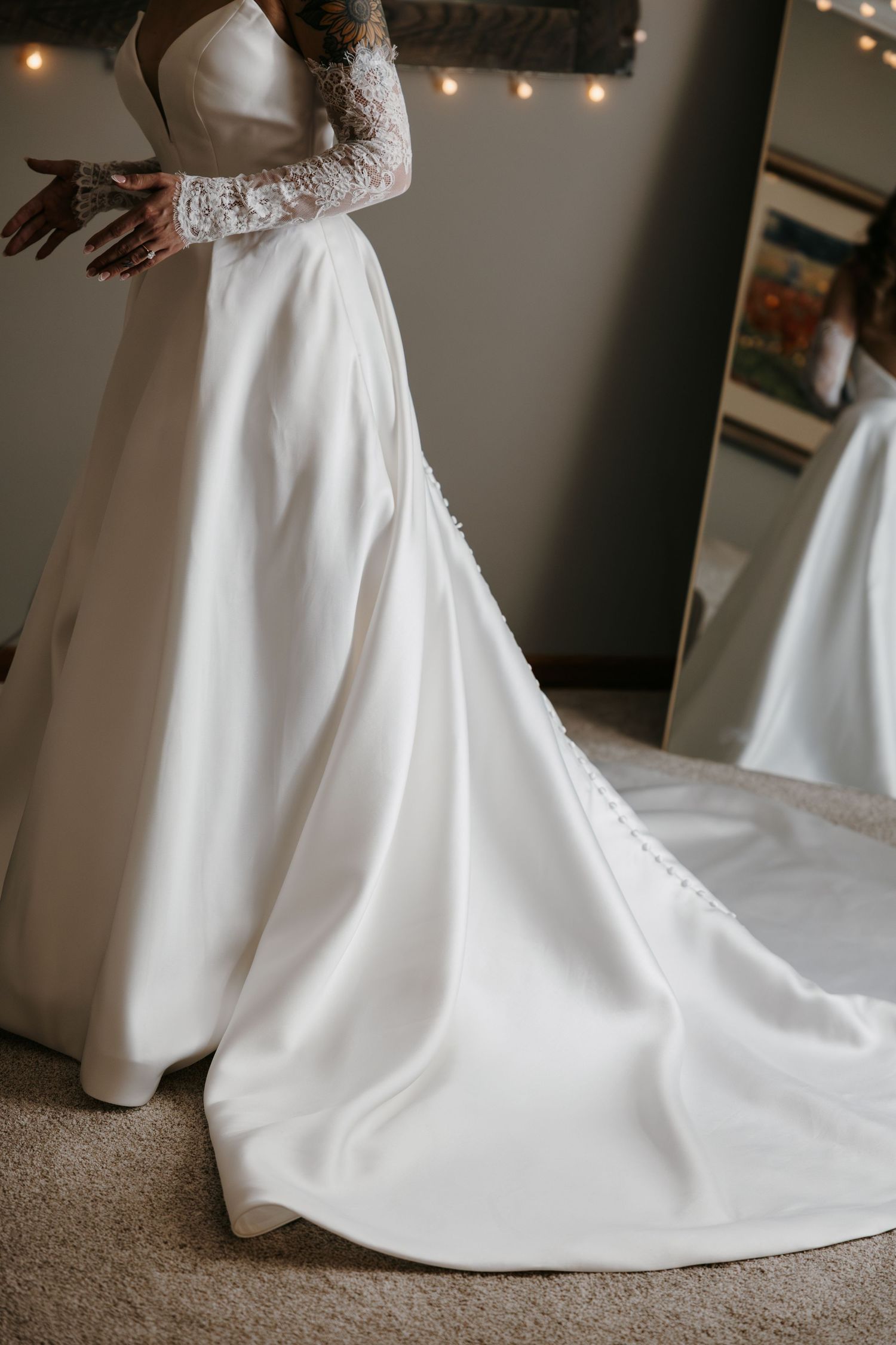 Detail shot of an elegant white wedding dress train with lace sleeves and buttons.