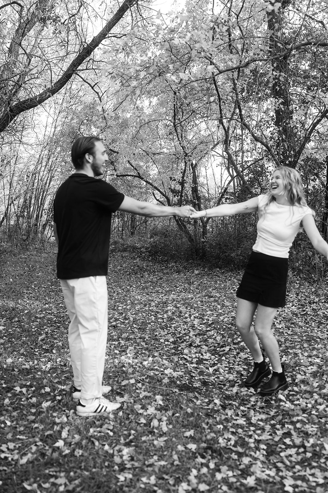 Black and white sequence of couple dancing in leaf-covered forest.