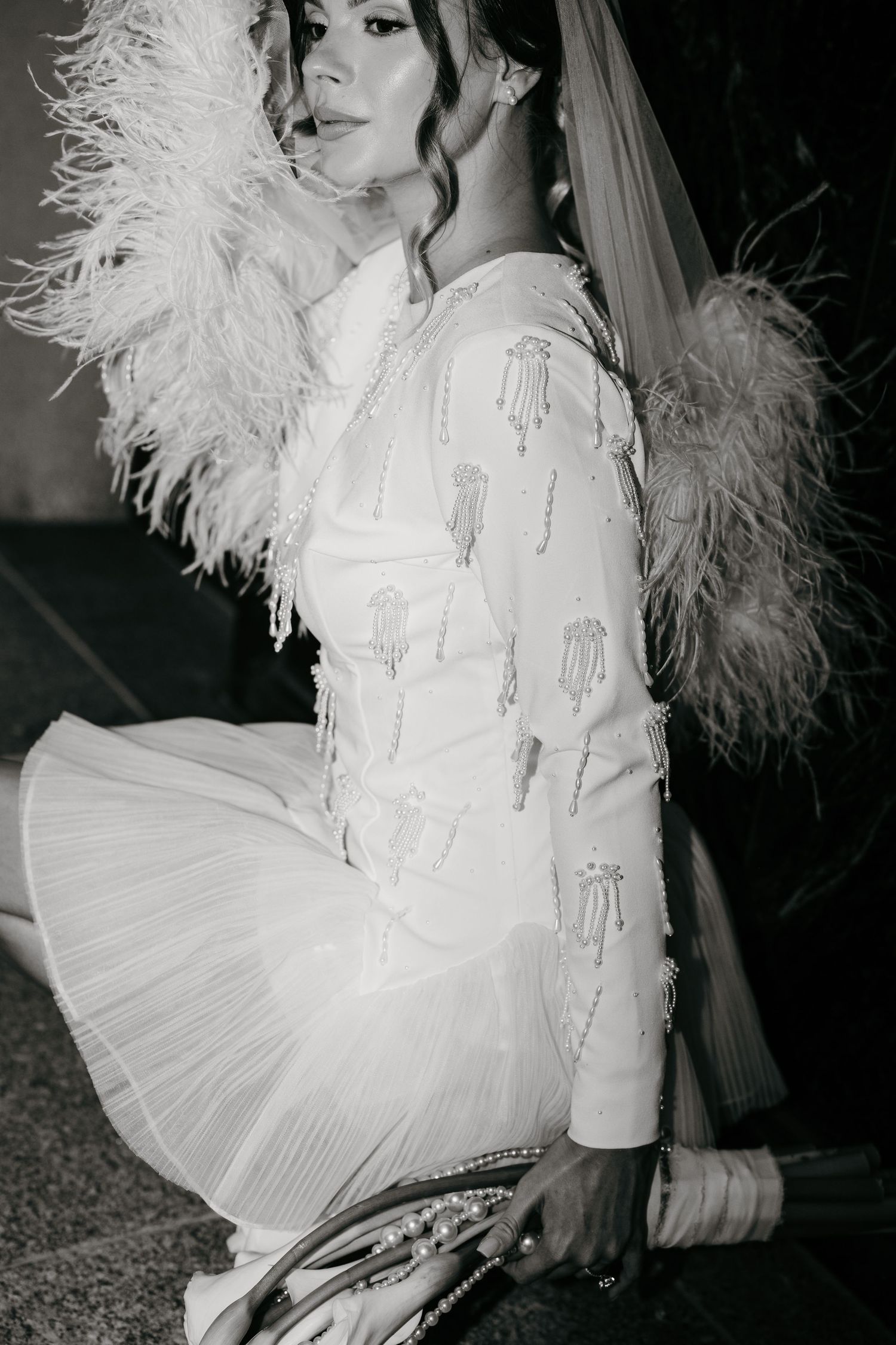 Elegant bridal dress with feather details and pleated skirt in black and white.