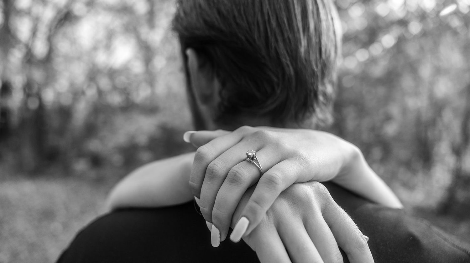 Black and white image of a couple's intimate embrace outdoors.