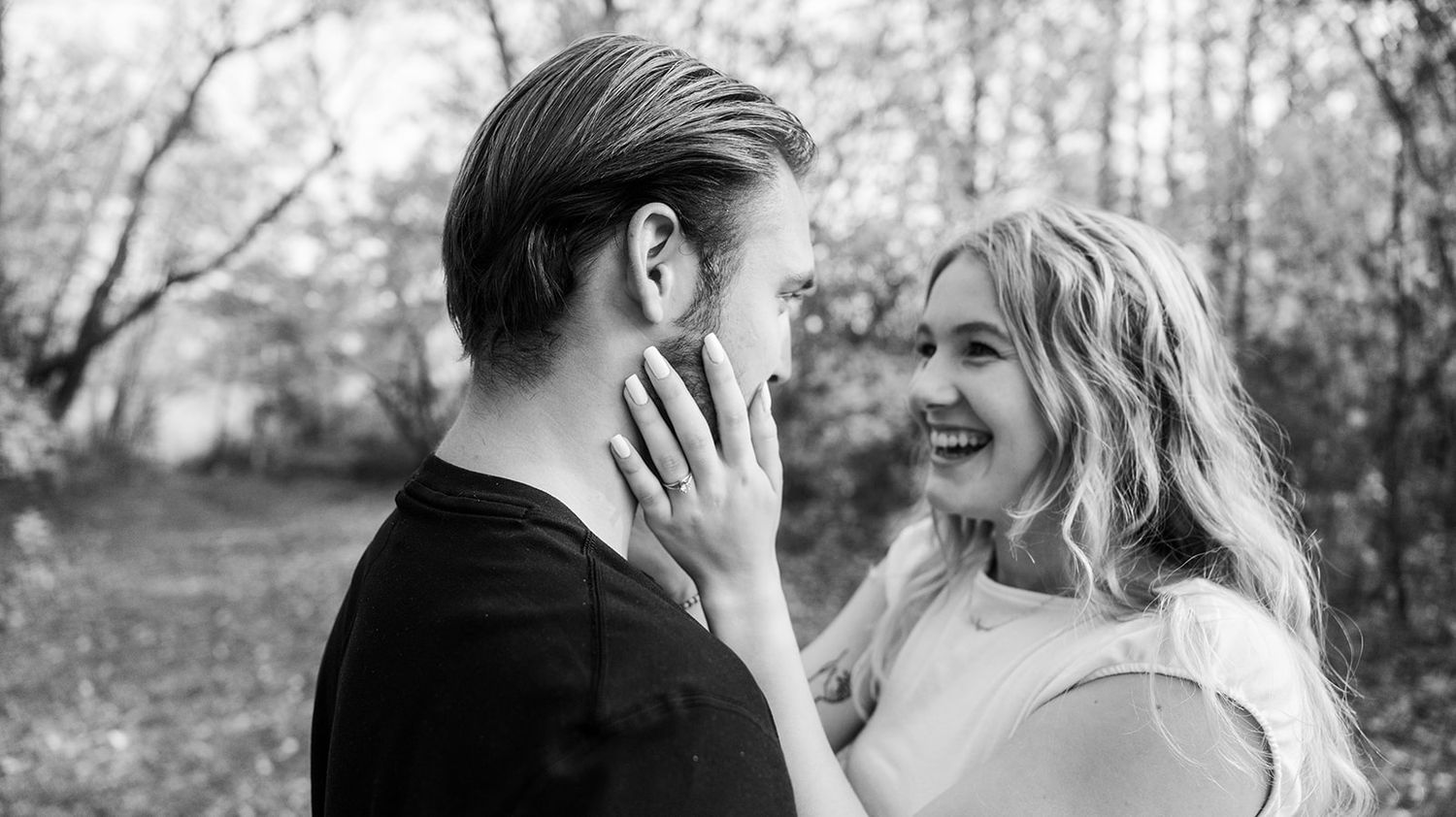 Black and white portrait of a couple sharing a tender moment outdoors.