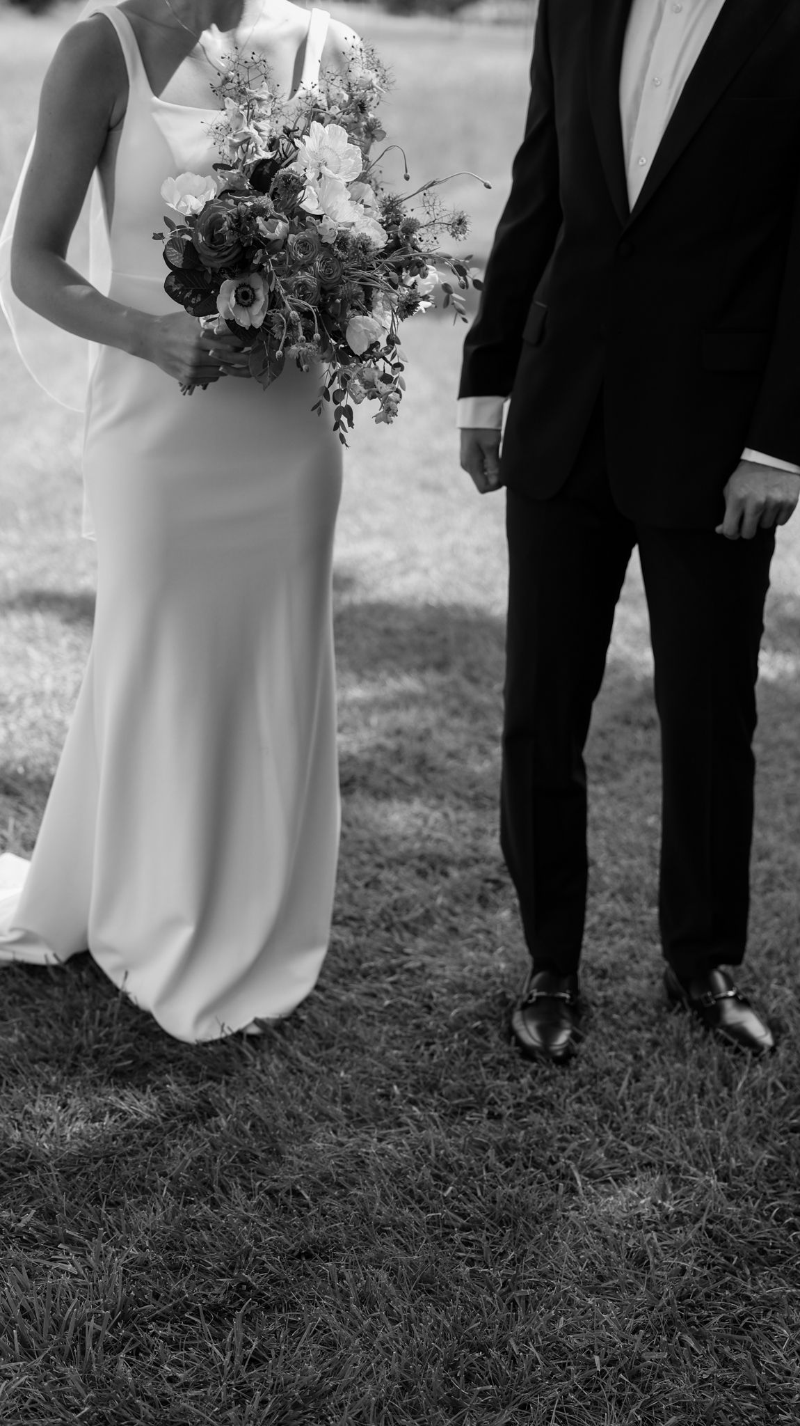 Black and white wedding photography showing formal attire and bouquet details.