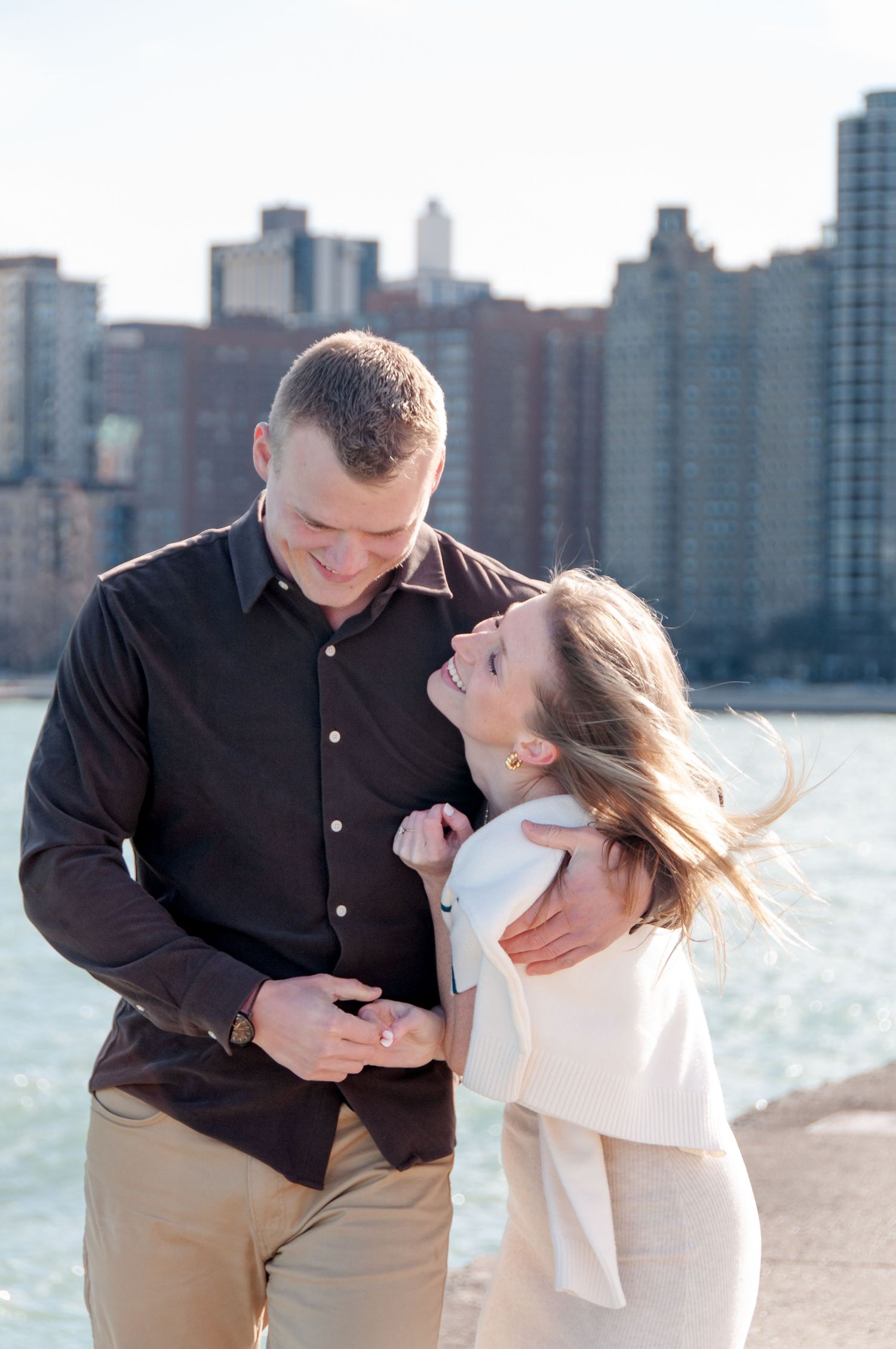 Engaged couple smiling and hugging along lakefront in downtown Chicago