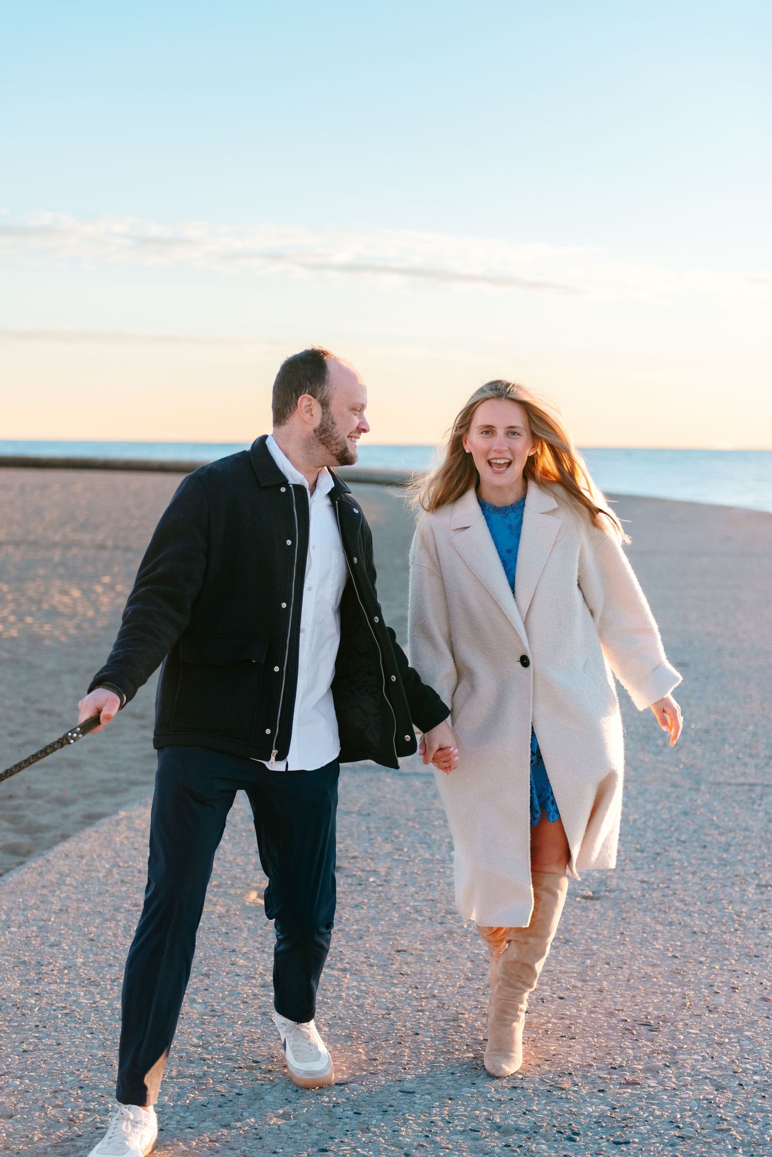 Couple holding hands and laughing during early morning Chicago lakefront engagement session