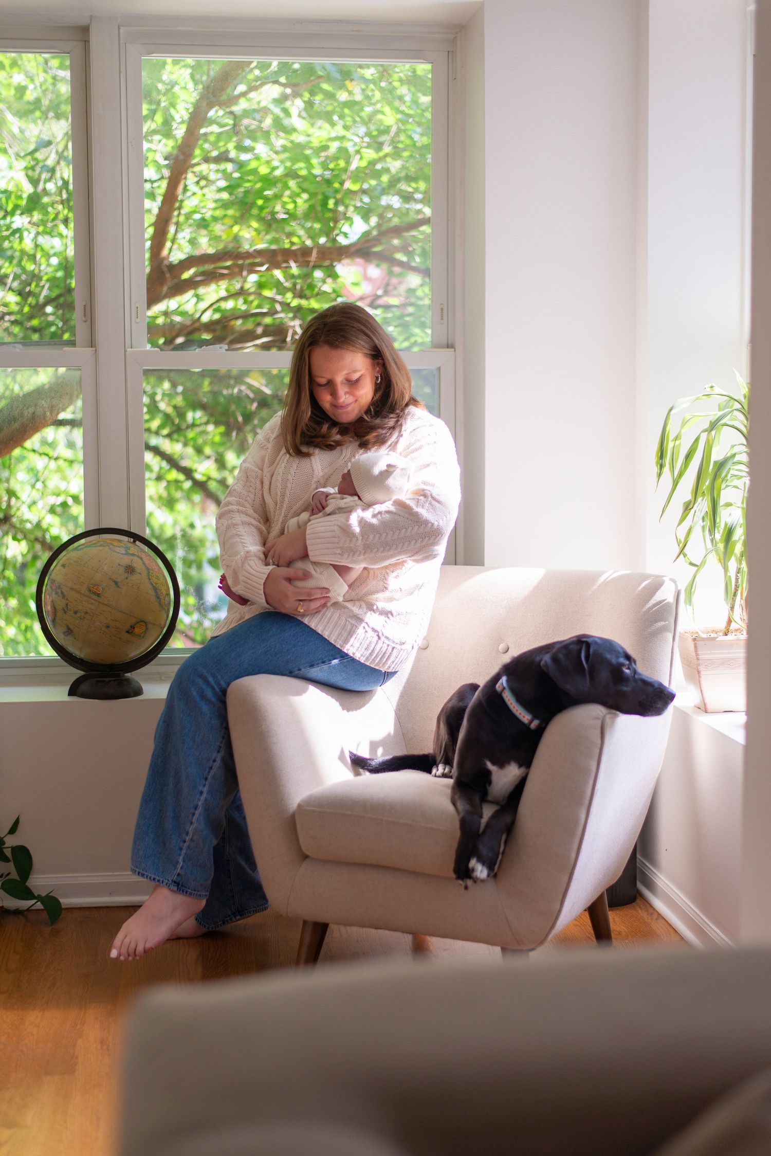 Mother cradling baby with family pet during newborn session