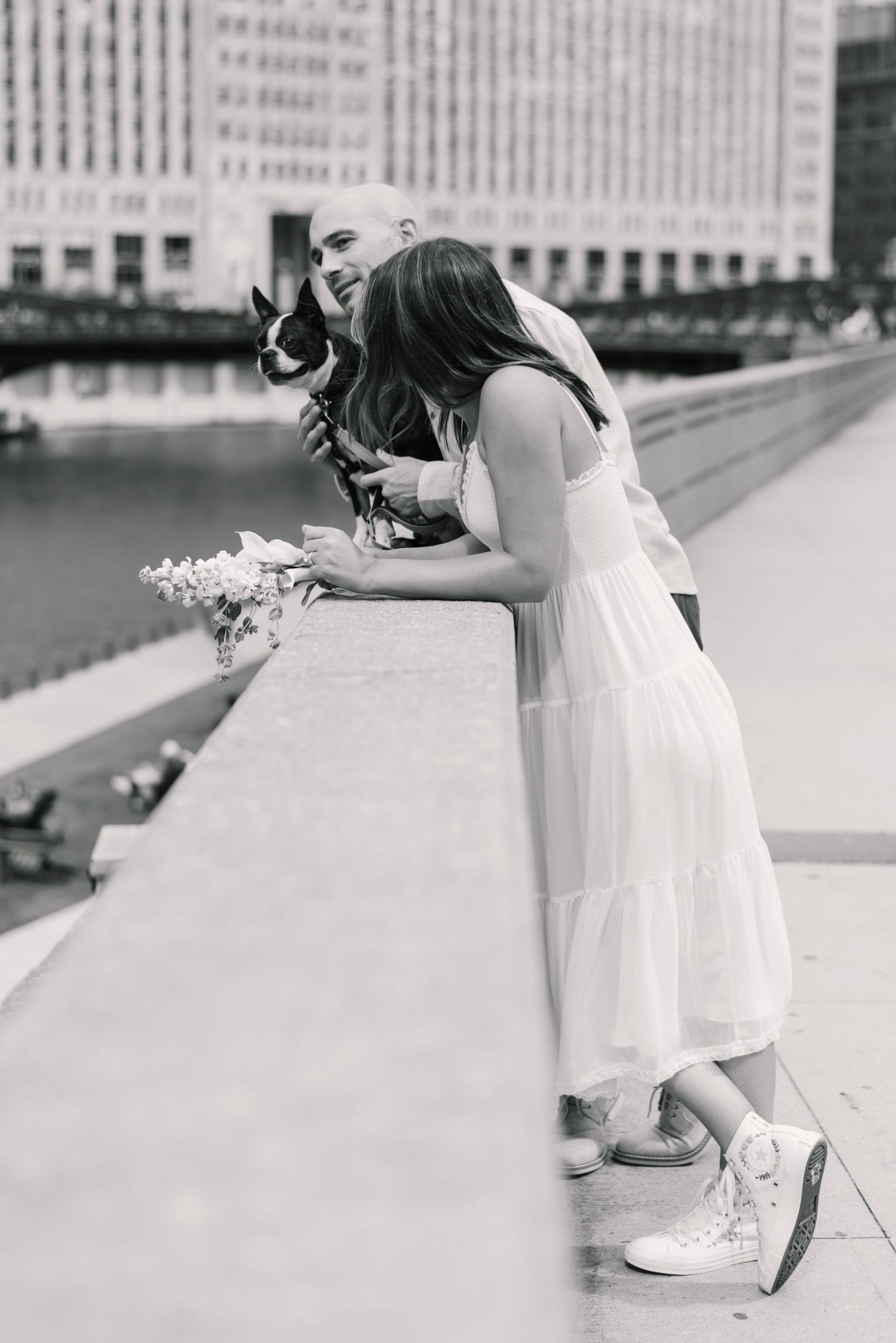 Bride and Groom leaning over the walkway of the Chicago Riverfront with their dog