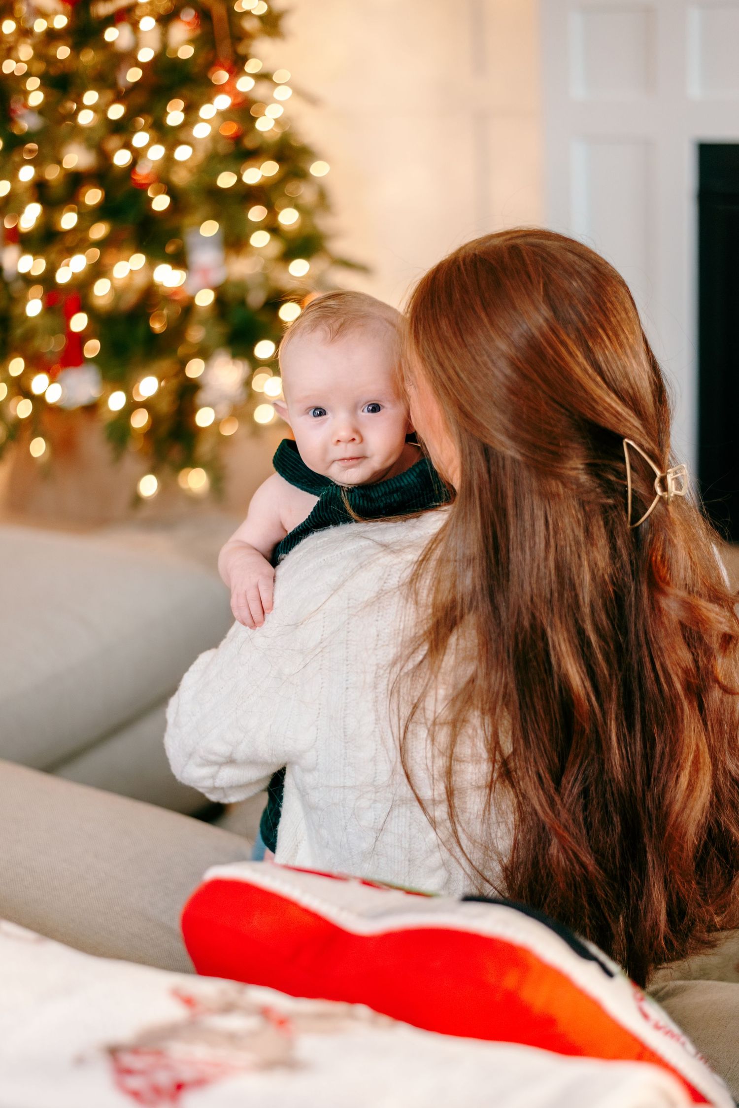 Mother kissing newborn during in-home Christmas family session