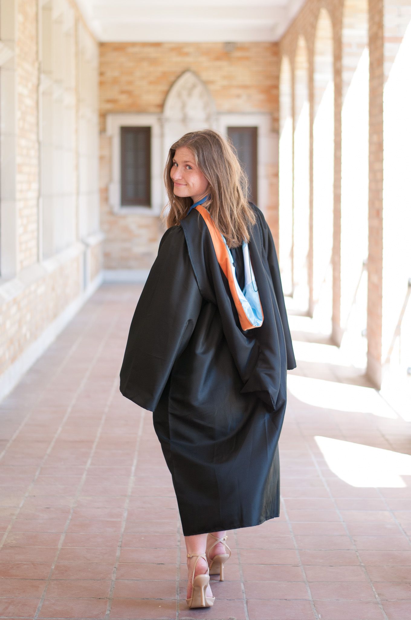 Graduate walking halls of college during senior photo session