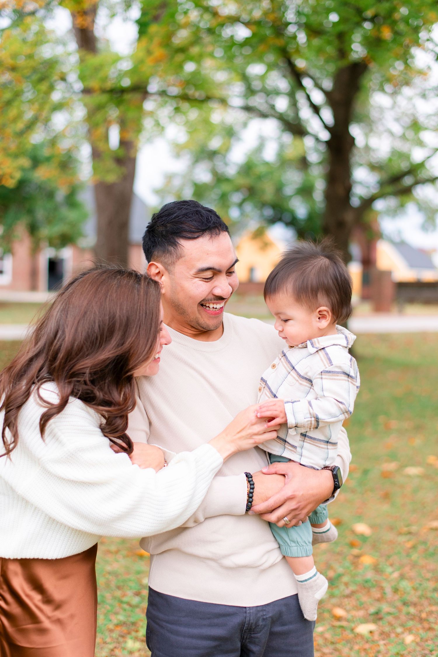 Father holding toddler while mom tickles during fall outdoor photo session
