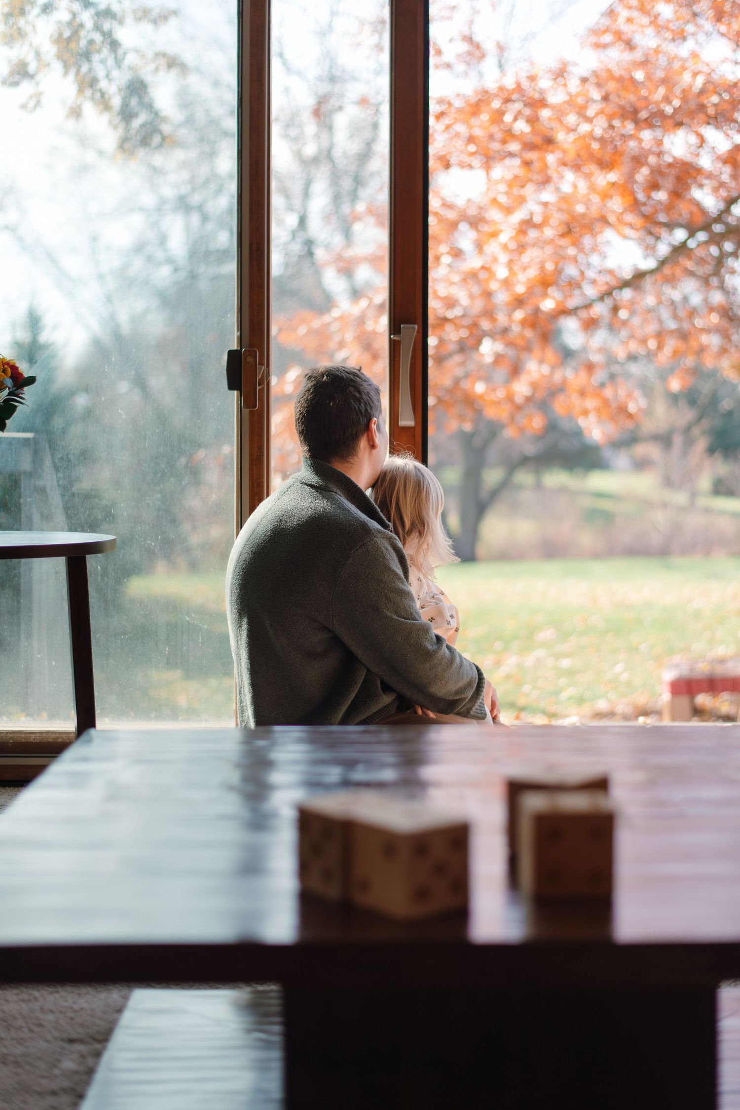 Father holding daughter while looking outside during family photography session