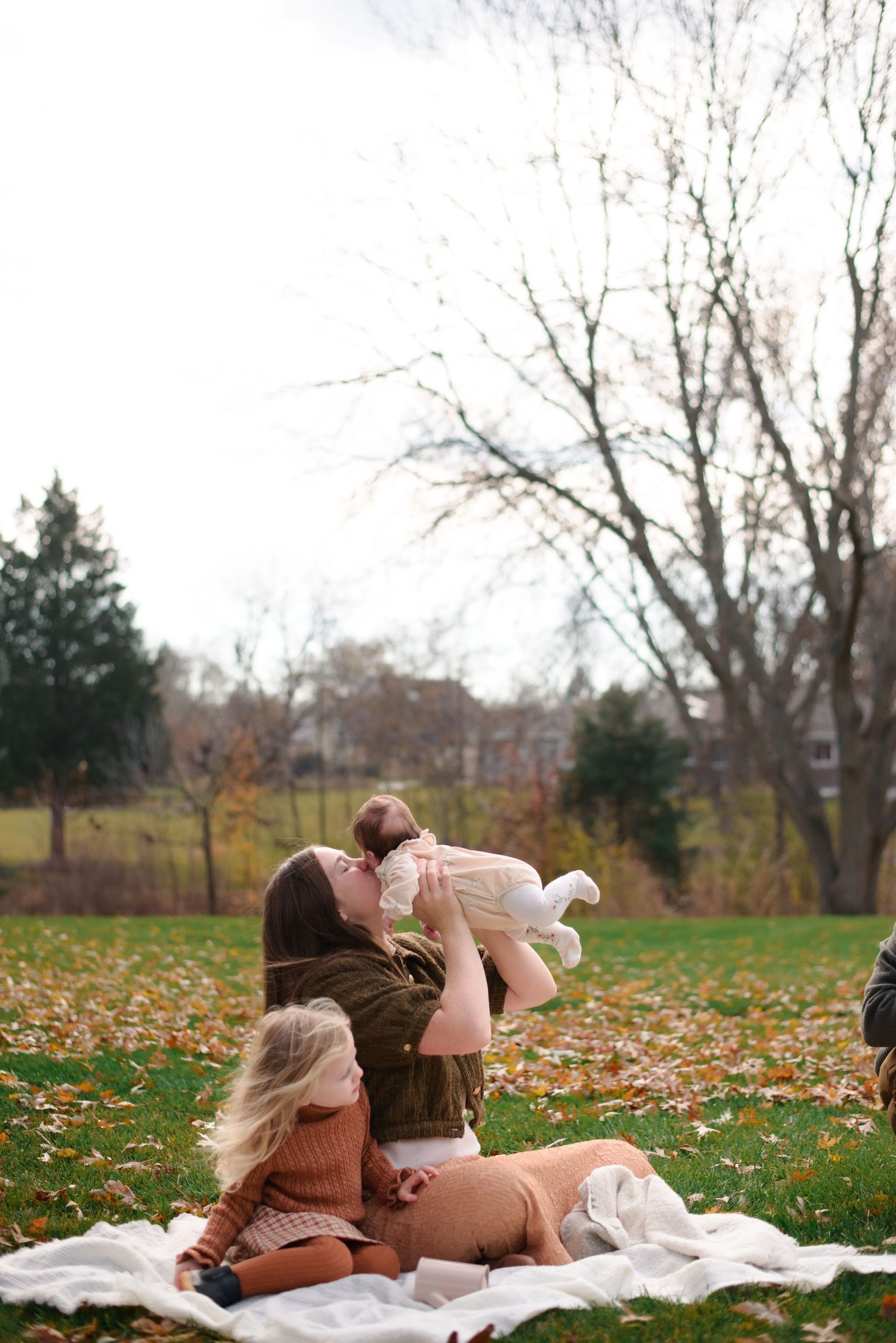 Mother airplanes baby and gives her kisses during family session