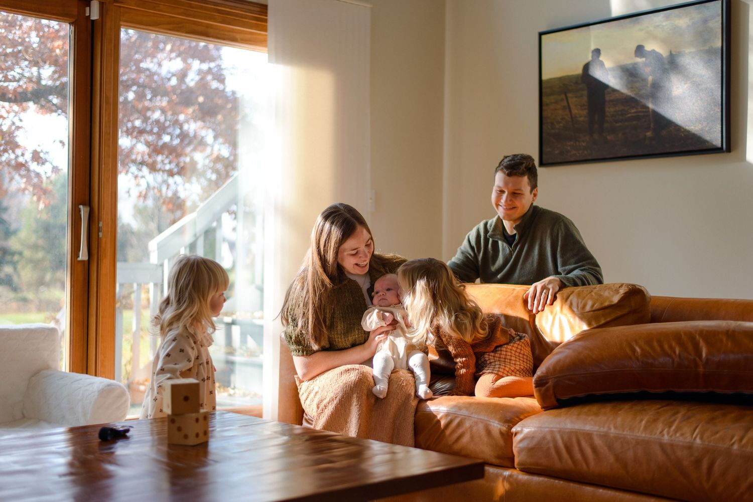 Family cuddling on couch during informal, documentary style photoshoot