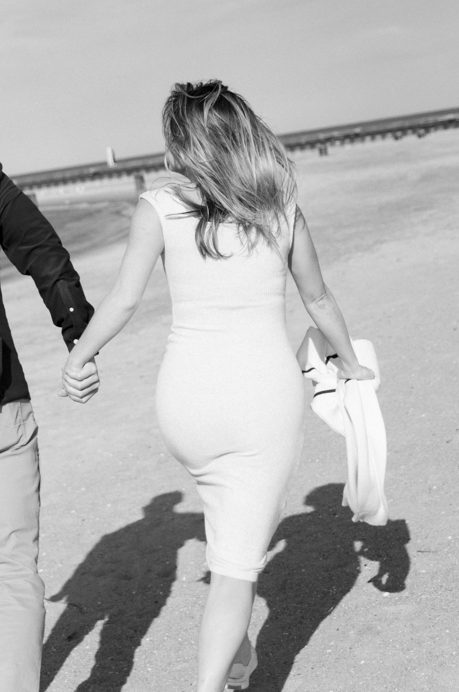 Couple running on beach together during documentary-style engagement session