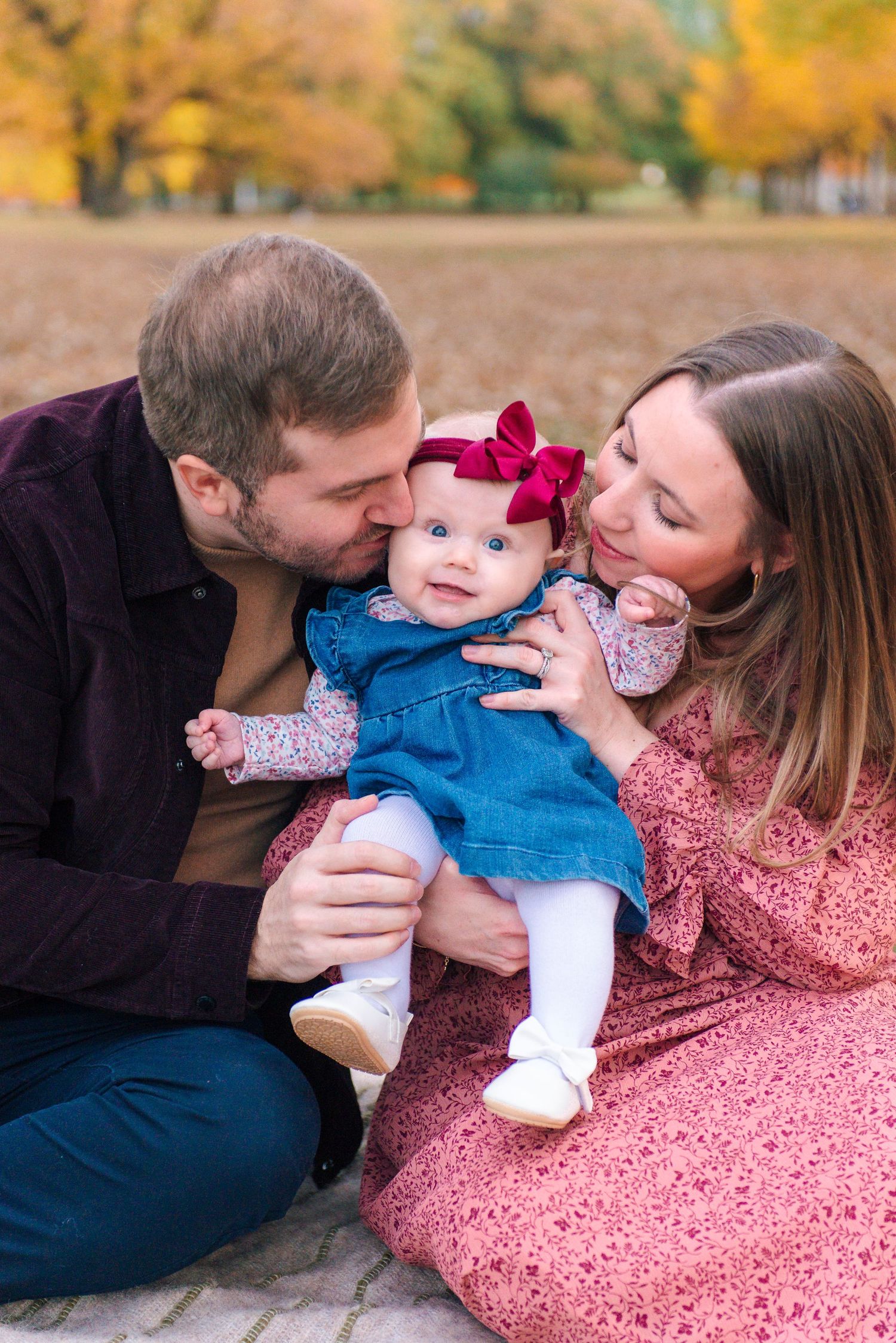 Parents kissing toddler during intimate fall family portrait session