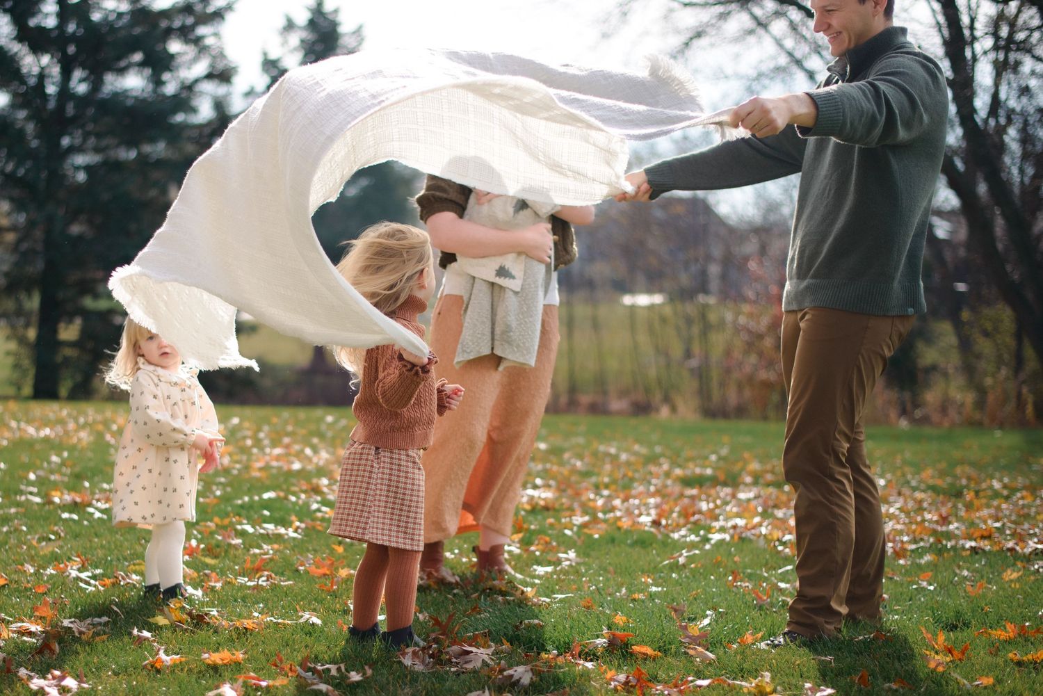 Wide shot of siblings playing under blanket during fun, informal family shoot
