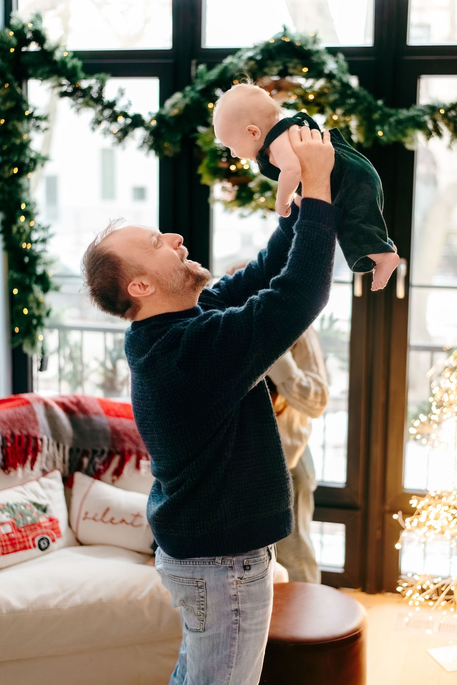 Father holding newborn up during in-home Christmas family session