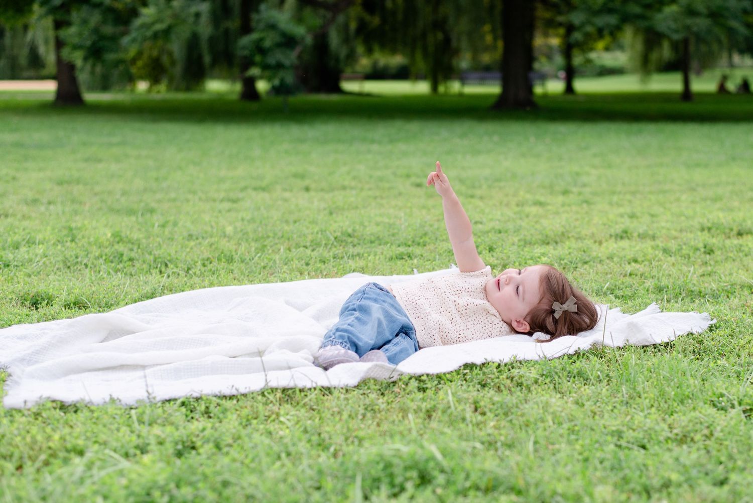 A toddler laying on a white picnic blanket during a family lifestyle photoshoot in north Chicago park