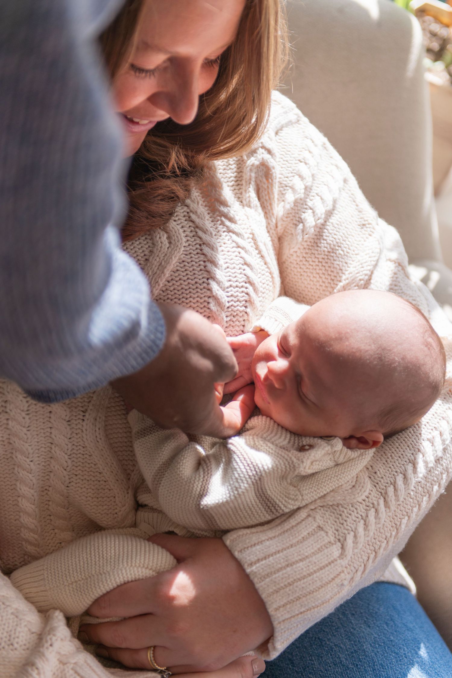 Mother cradling baby, while father reaches down to touch their face during family session