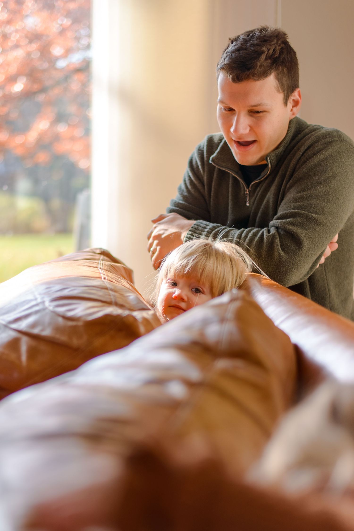 Daughter hiding and playing on couch during family lifestyle photo session