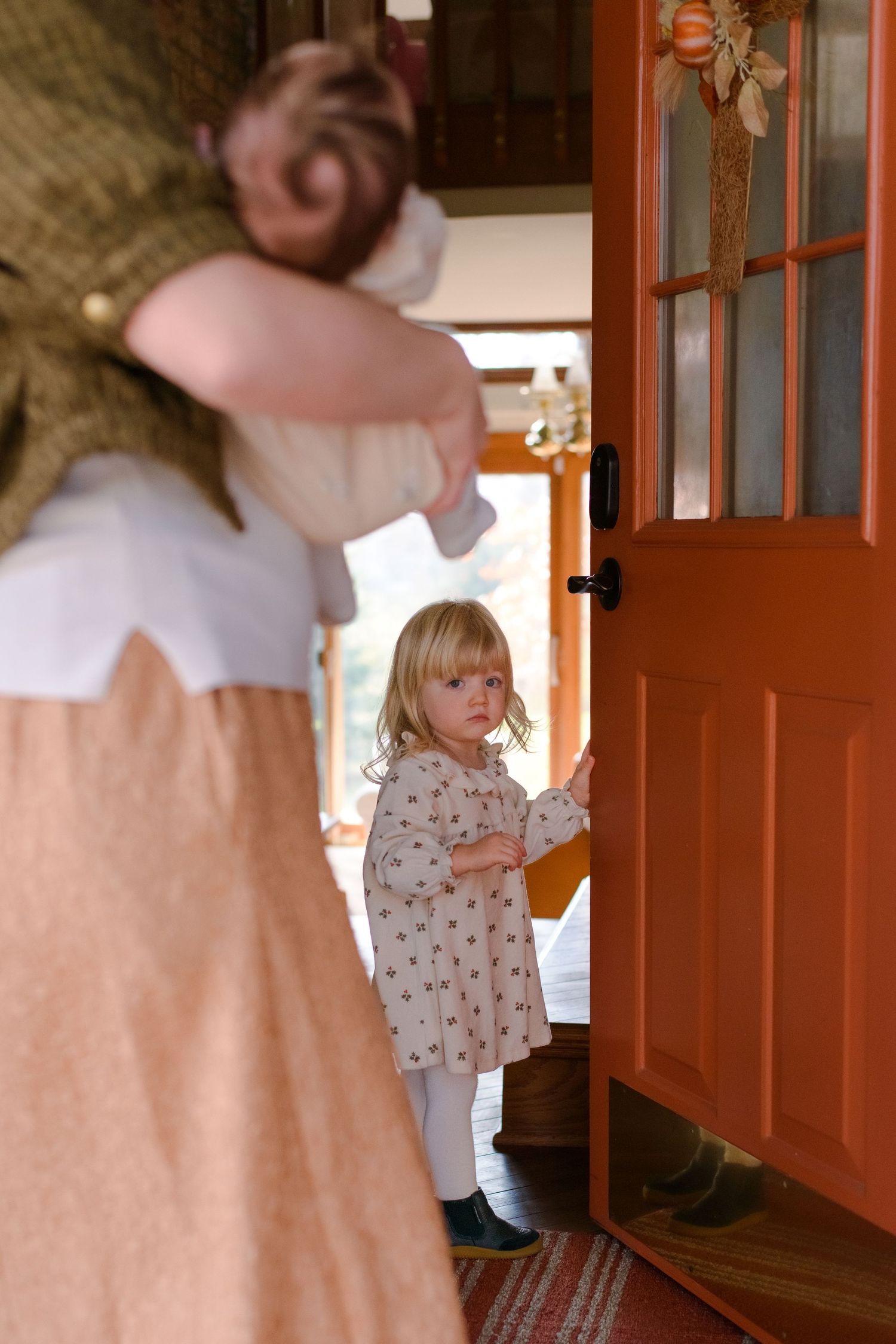 Daughter opening the front door to welcome in photographer during family session