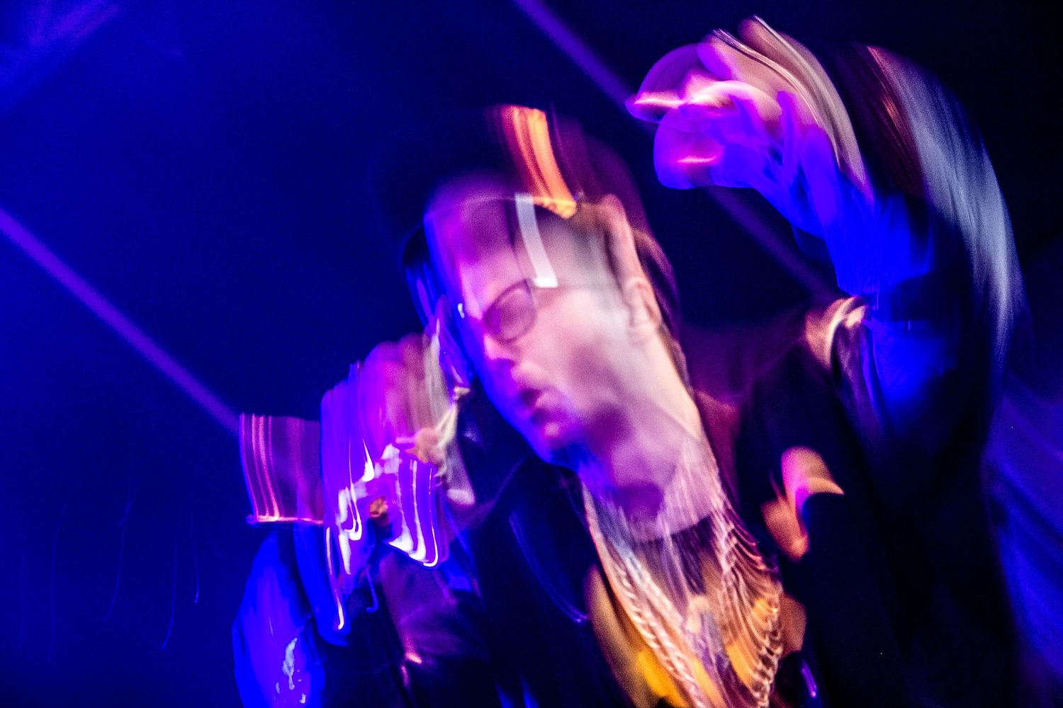 Dynamic concert photography with motion blur in deep blue stage lighting.