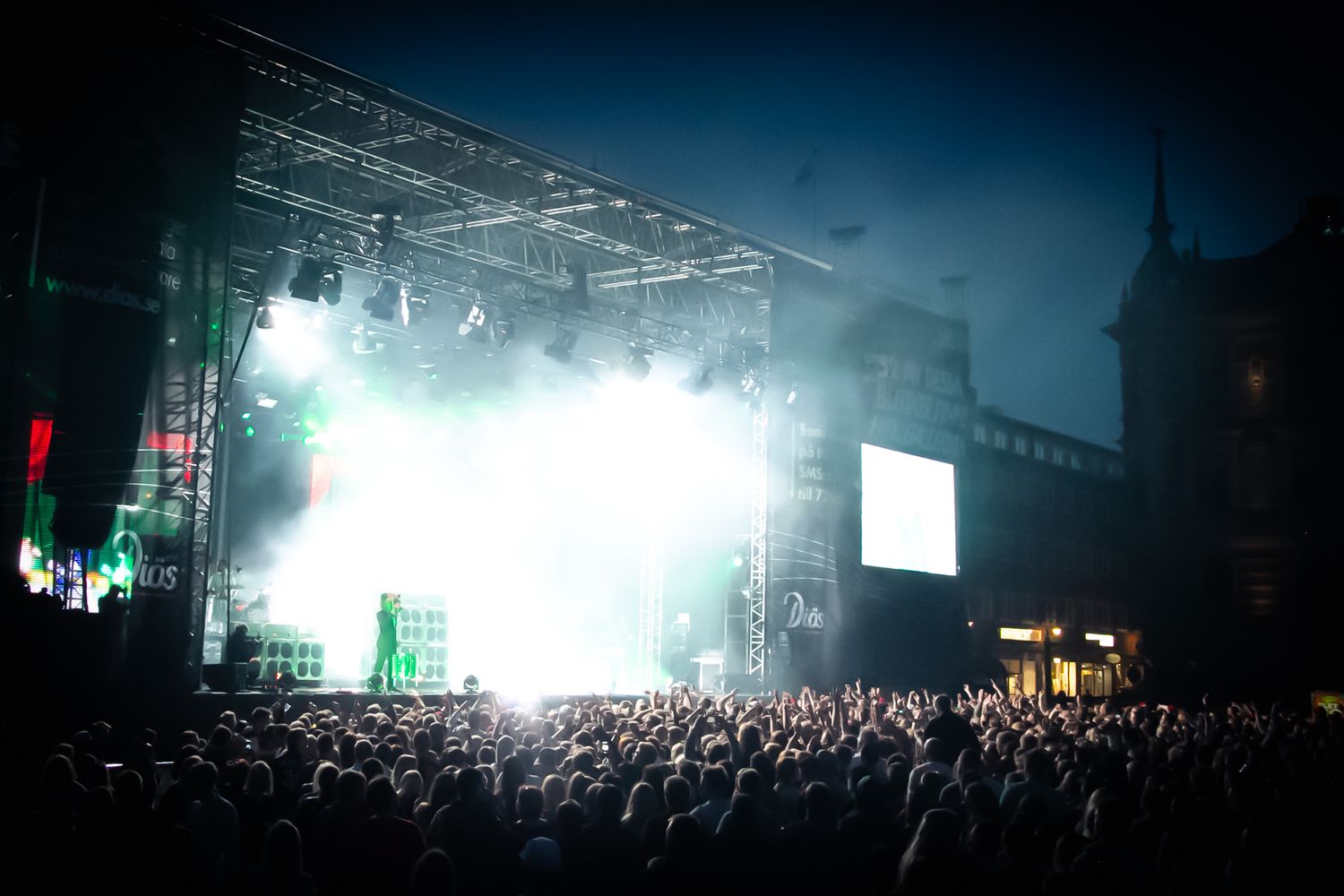 Concert venue filled with crowd silhouettes and bright stage lighting creating atmospheric ambiance.