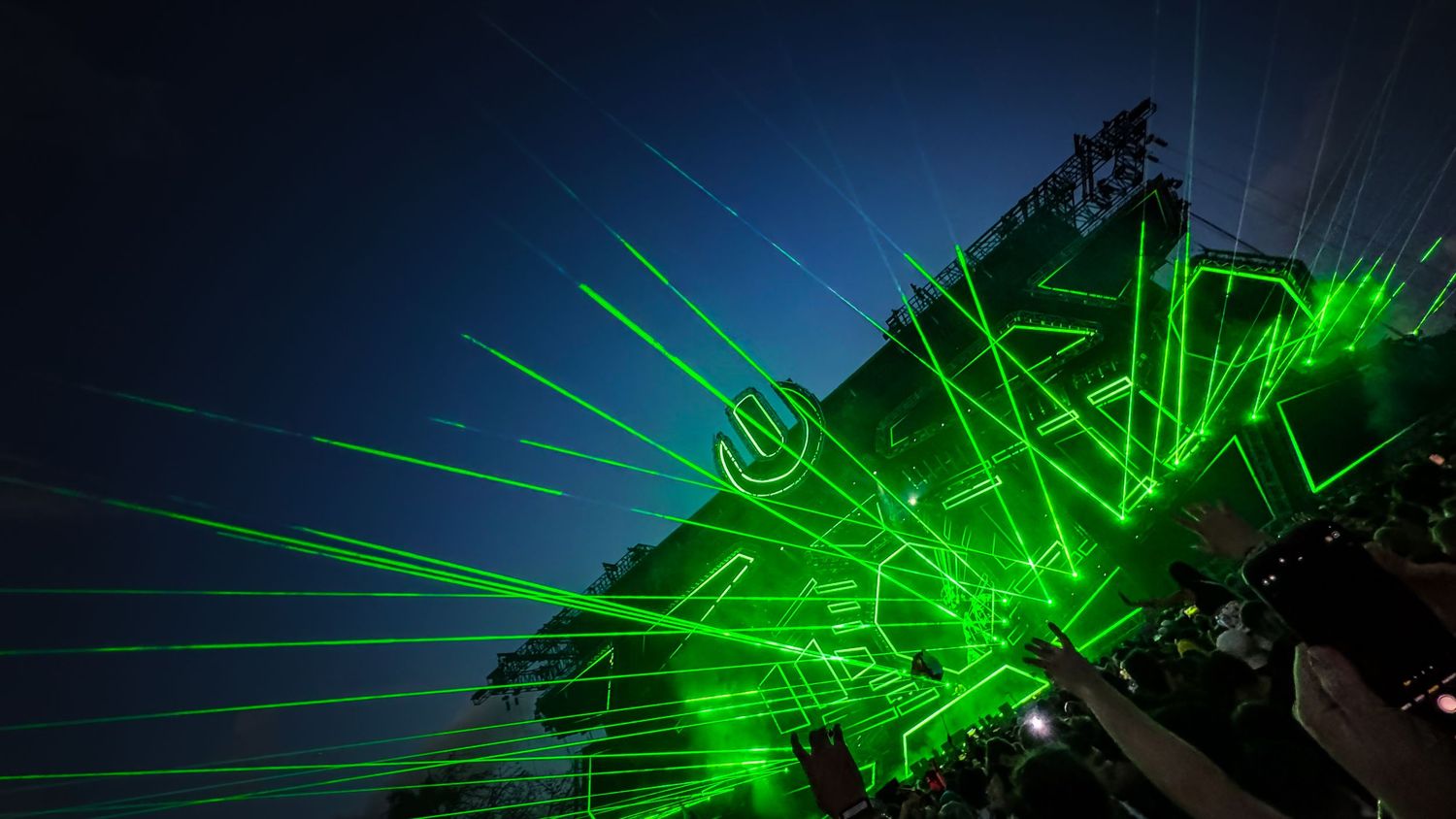 Abstract green laser light show creating geometric patterns against a dark background.