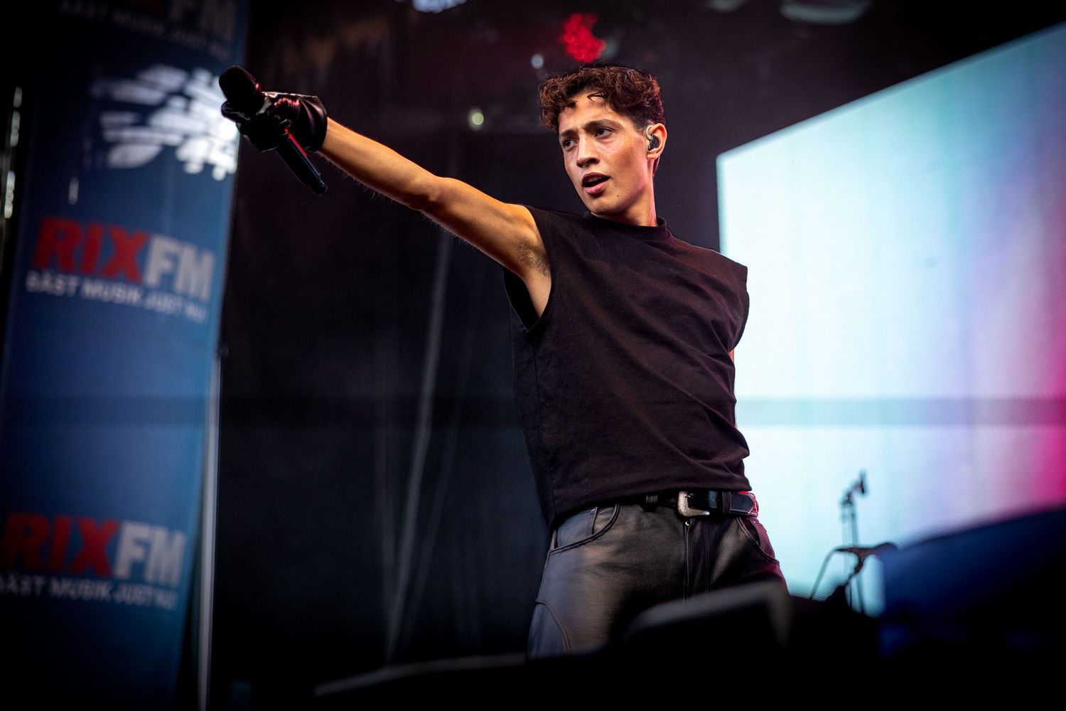 Music festival performance on stage with blue lighting and professional setup.