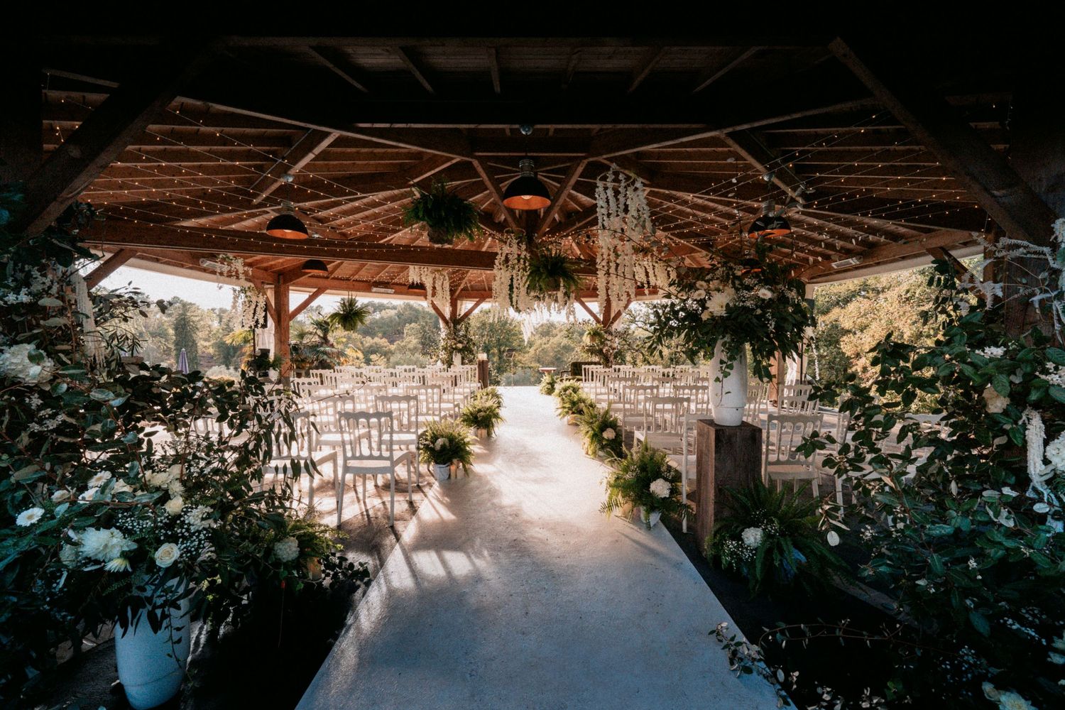 Lieu de cérémonie de mariage décoré, ambiance bohème et végétale, lumière dorée.