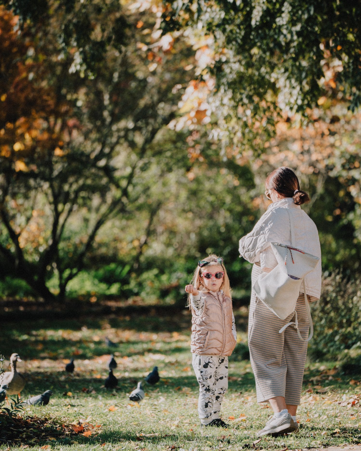 Portrait lifestyle de famille dans un parc arboré, lumière naturelle, ambiance douce et automnale.