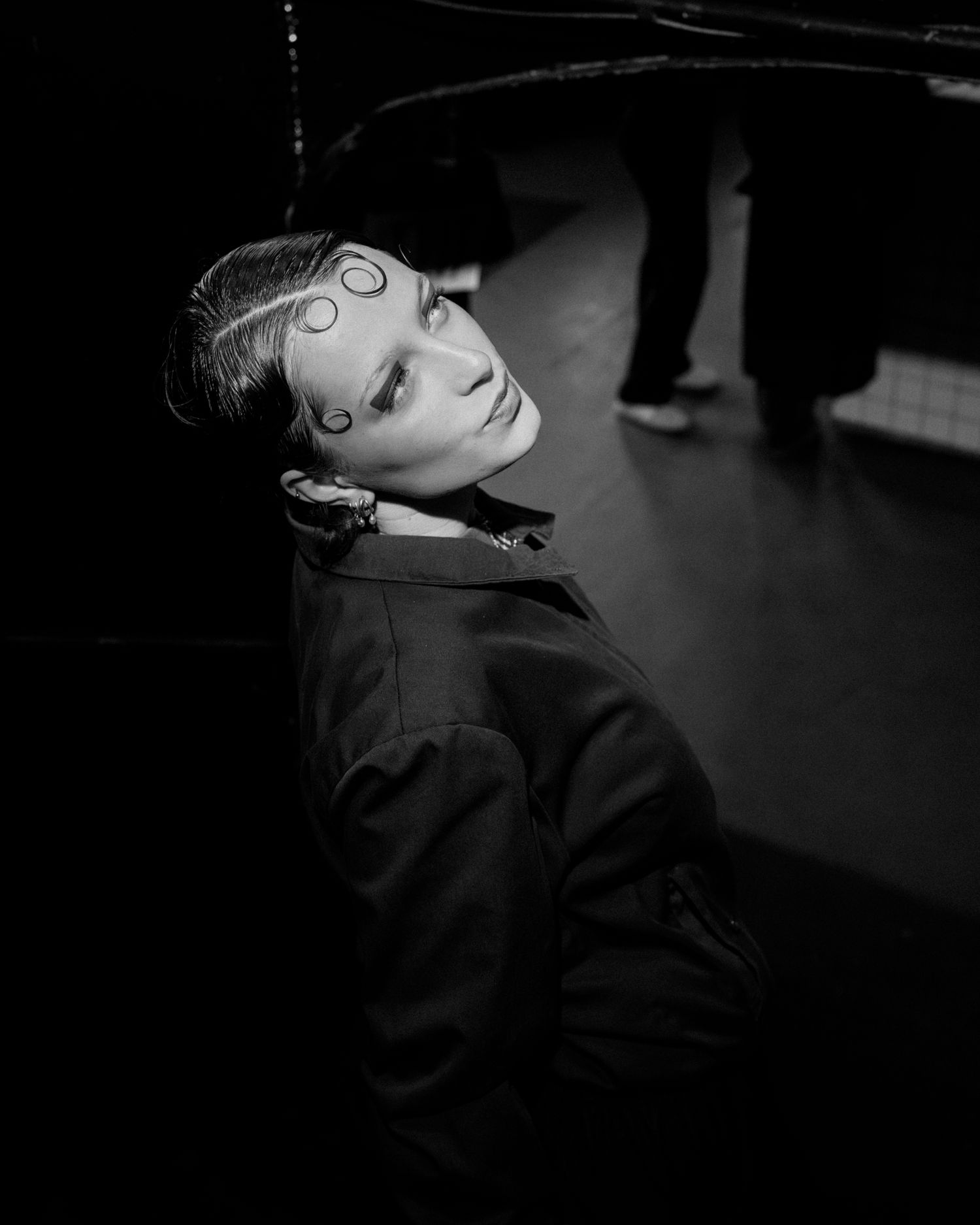 Model en noir et blanc sur scène, lumière dramatique et ambiance cinématographique.