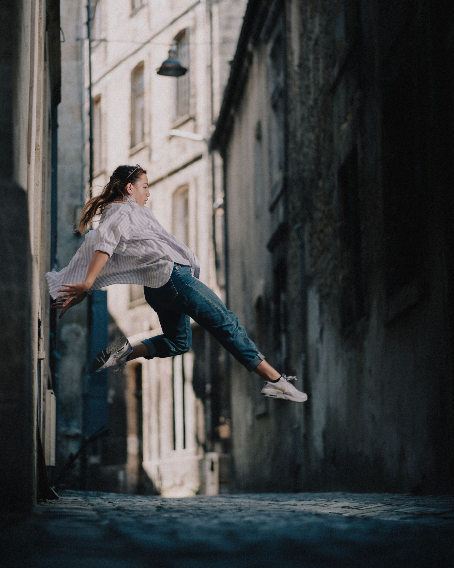 Saut de danseur capturé en suspension dans une ruelle sombre, photo artistique à Bordeaux.