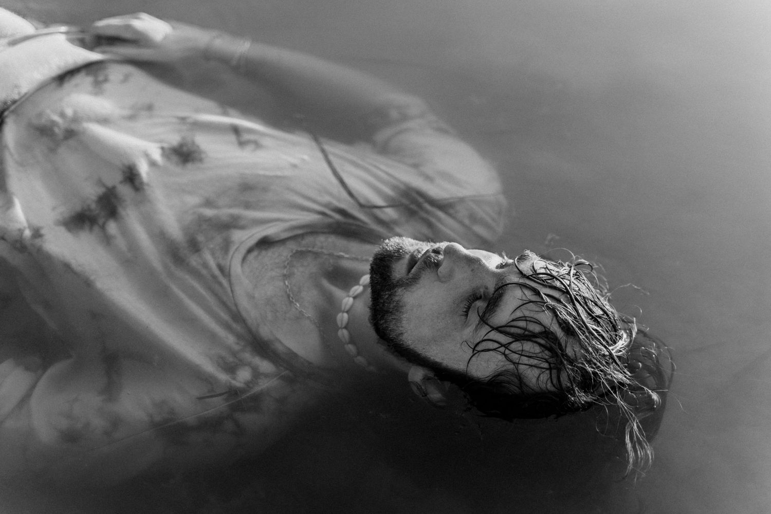 Corps flottant dans l’eau, ambiance onirique et pose introspective capturée en noir et blanc.