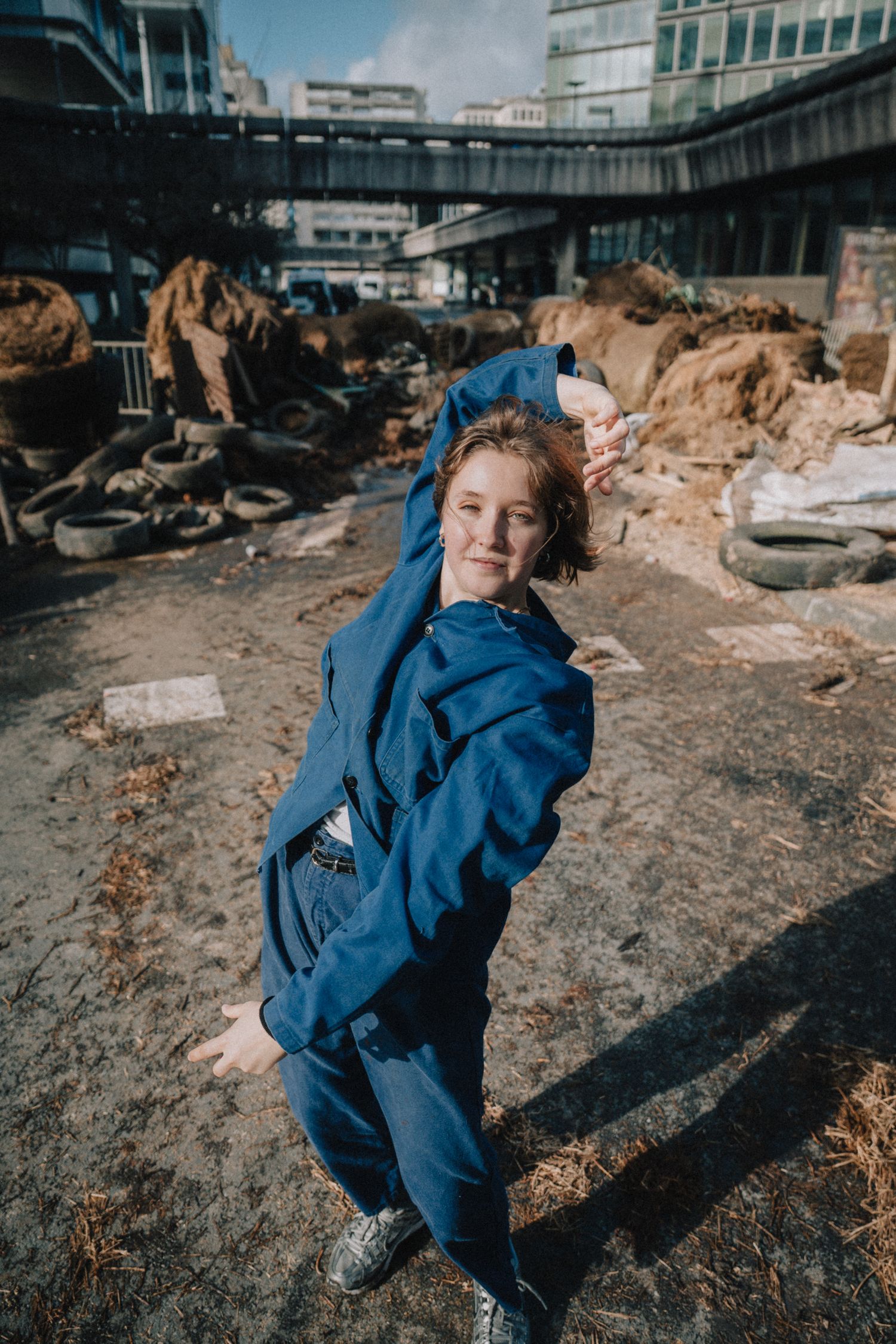 Portrait mode dans un décor industriel, contraste entre élégance et chantier urbain.