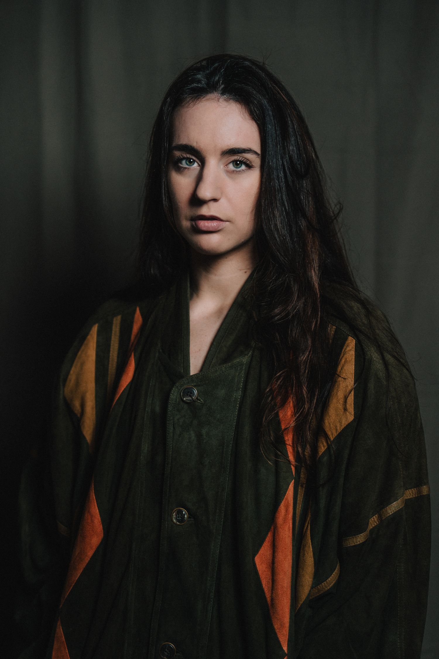 Portrait de femme au regard profond, ambiance douce et sobre, lumière tamisée sur fond sombre.