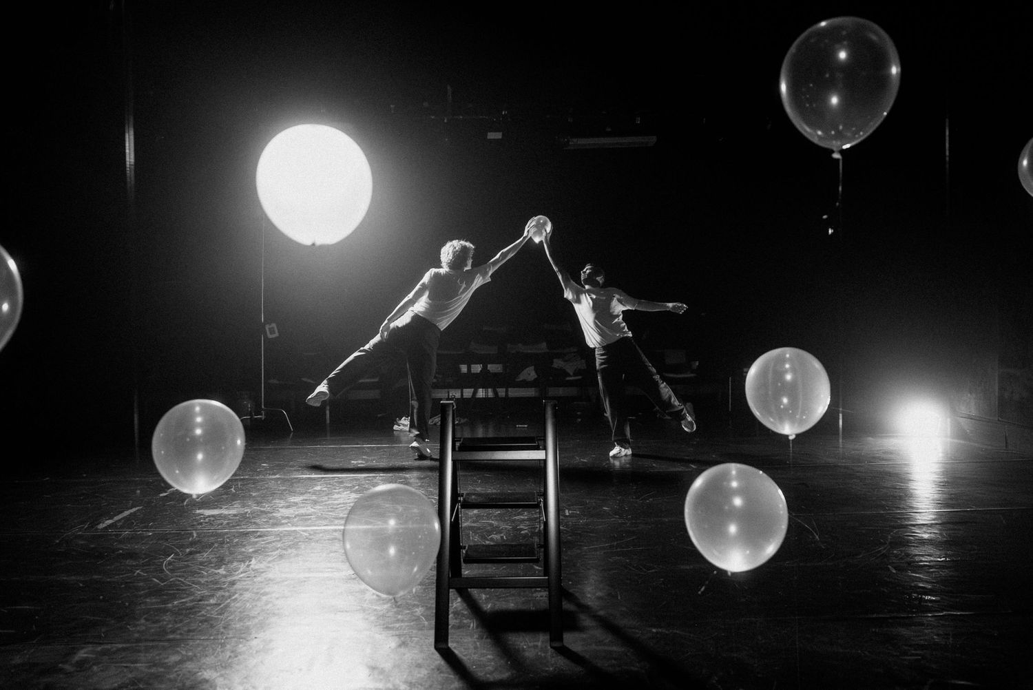 Création chorégraphique sur scène, ambiance onirique en noir et blanc, lumière dramatique.