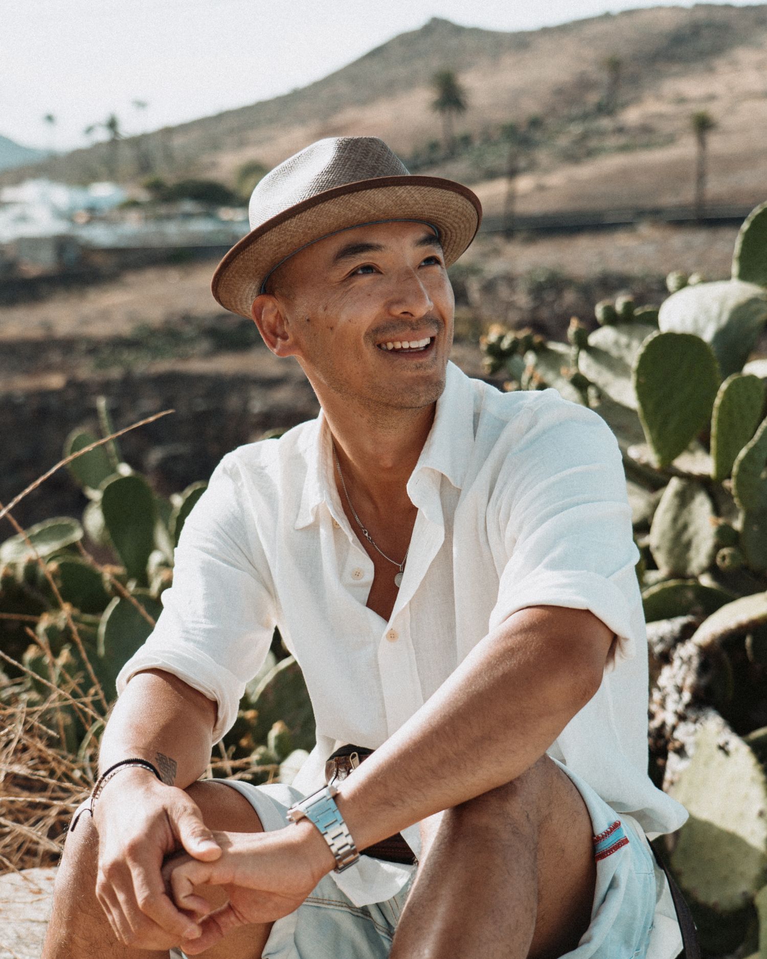 Portrait souriant d’un homme en chapeau sous le soleil, ambiance estivale et naturelle dans un décor méditerranéen.