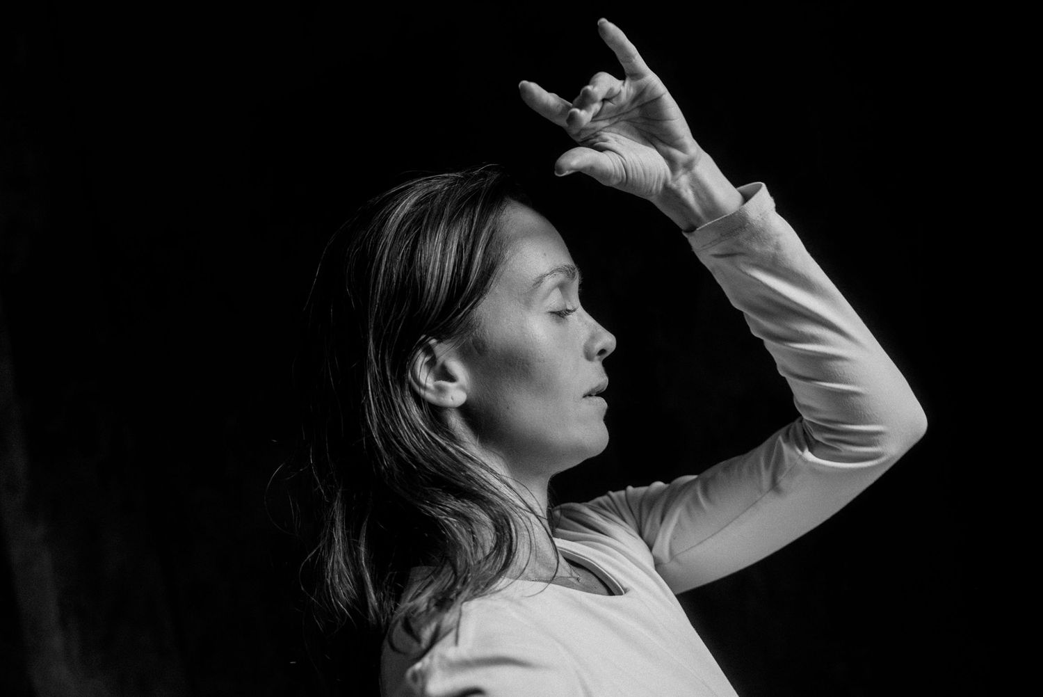 Portrait artistique en noir et blanc d’une femme en lumière douce, geste expressif, capté en studio dans un projet intimiste.