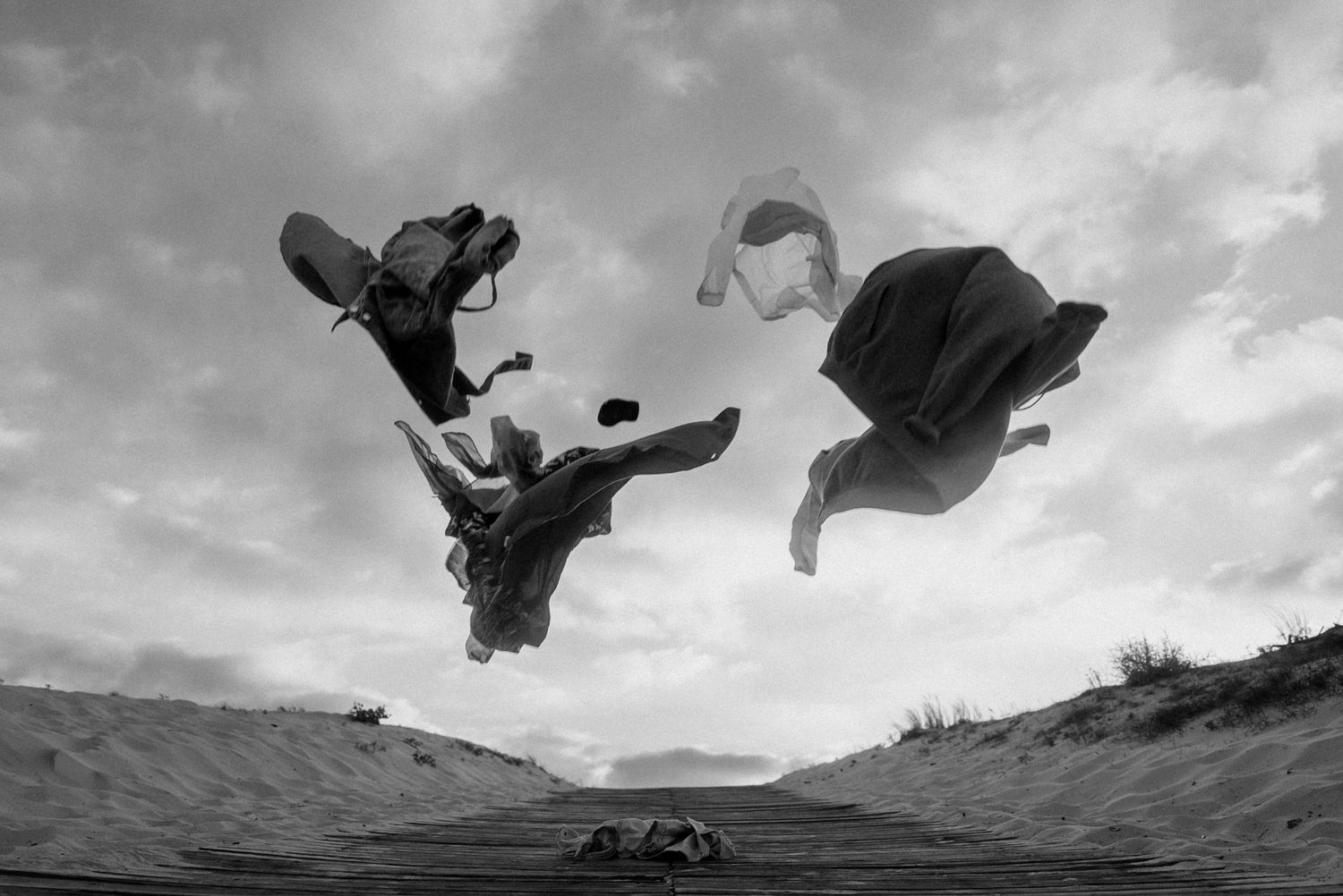 Vêtements suspendus dans les airs en noir et blanc, photo artistique abstraite prise en extérieur pour un projet chorégraphique visuel.