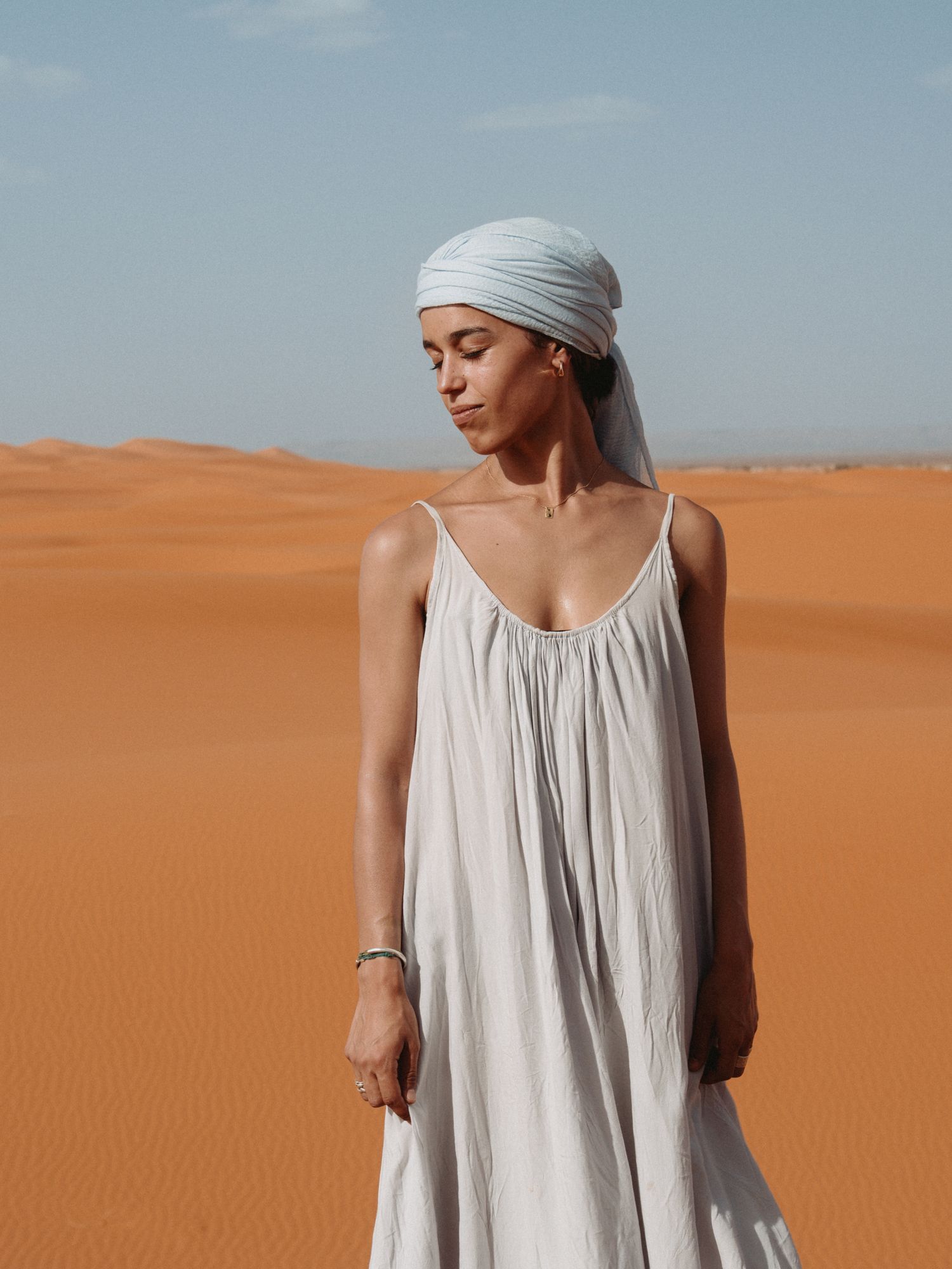 Portrait mode d’une femme dans les dunes, lumière naturelle, ambiance désertique.