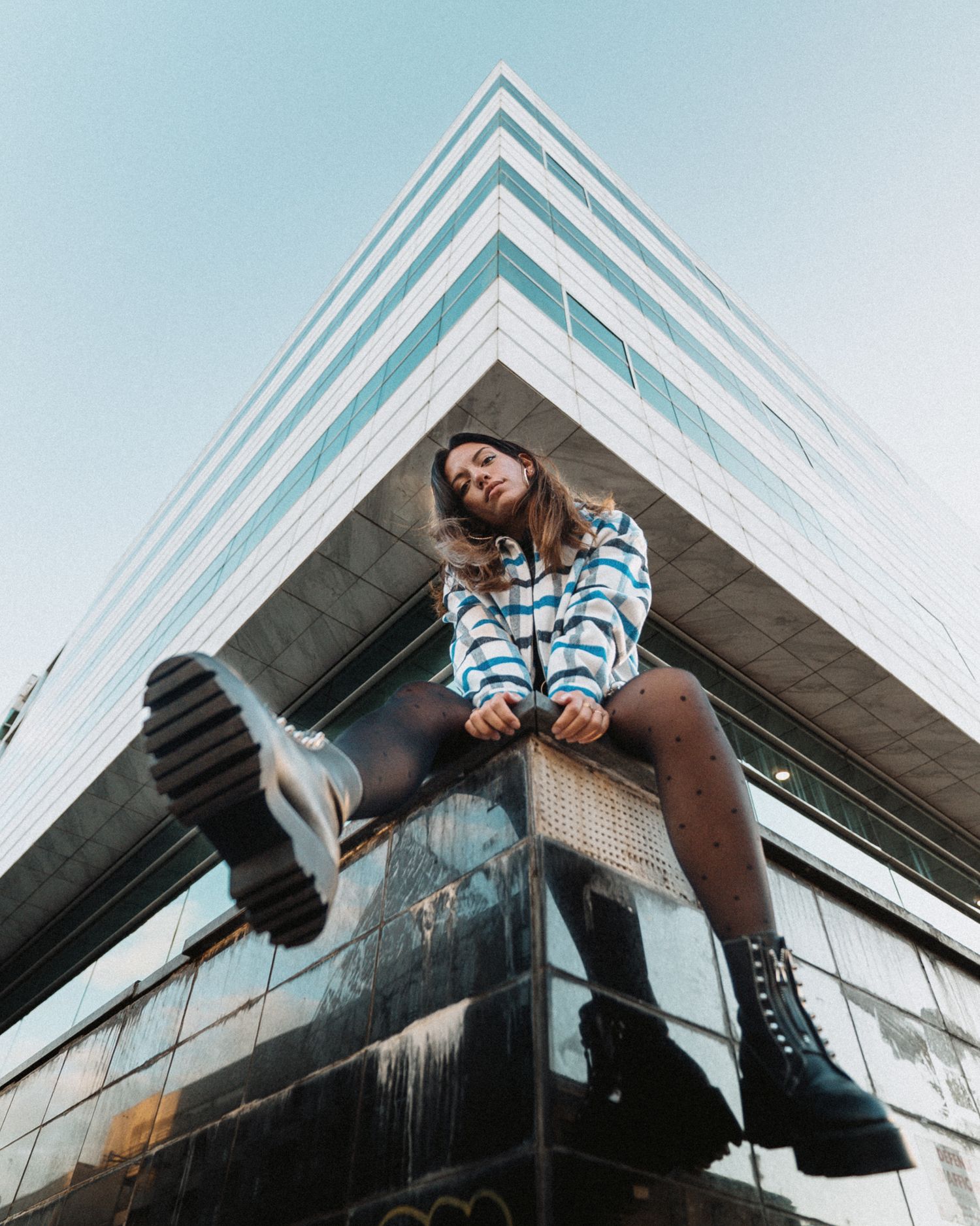 Portrait dynamique en contre-plongée, fusion entre attitude urbaine et géométrie architecturale.