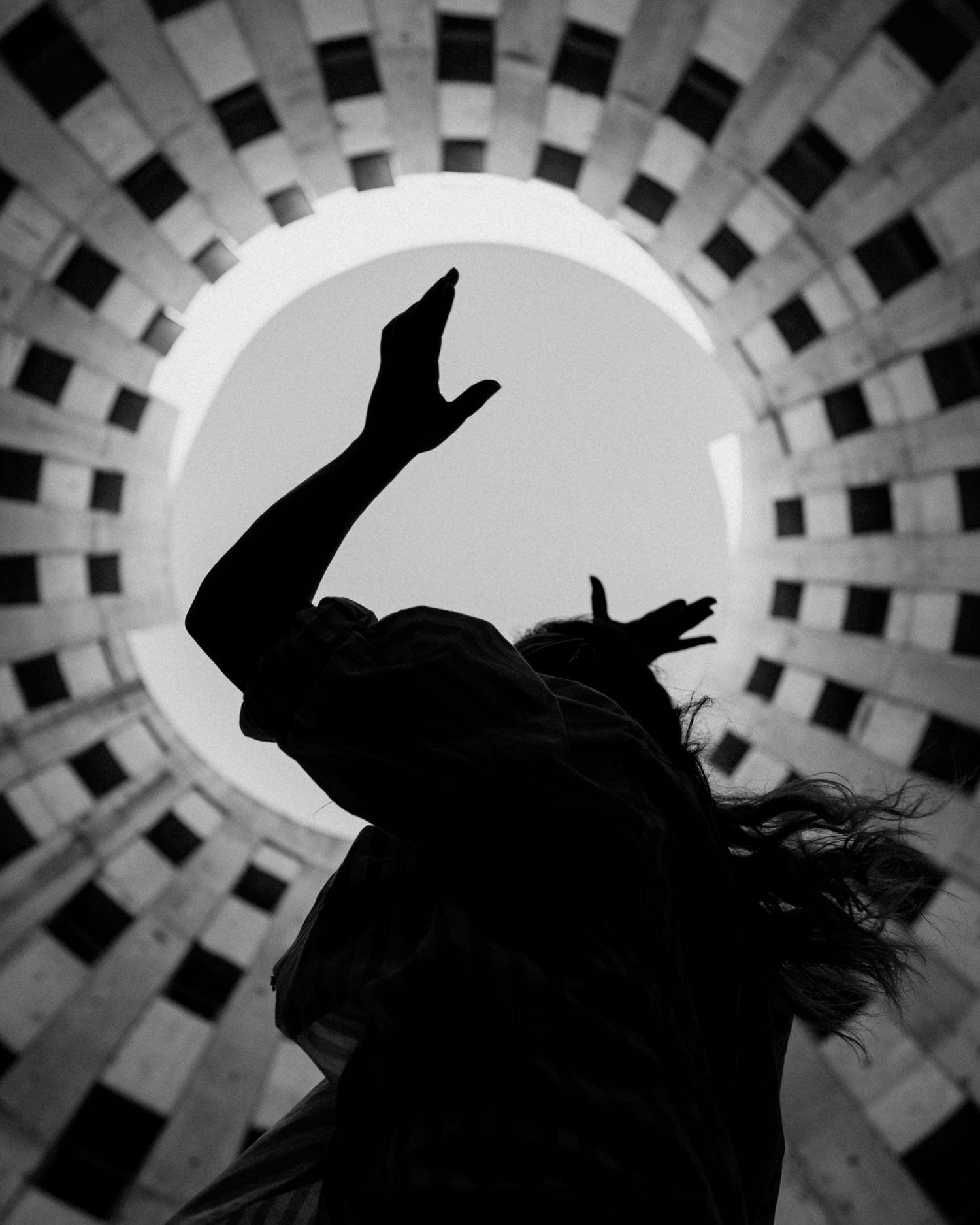 Silhouette dansante en contre-jour, sous une coupole géométrique, tension graphique et énergie brute.