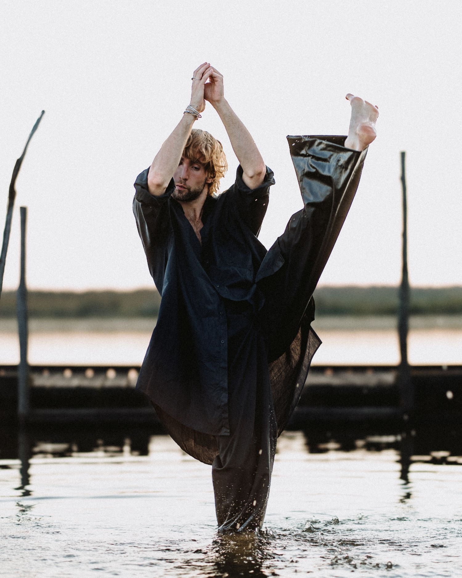 Danseur exécutant un grand écart dans l’eau, photo artistique capturée en bord de lac ou de ponton
