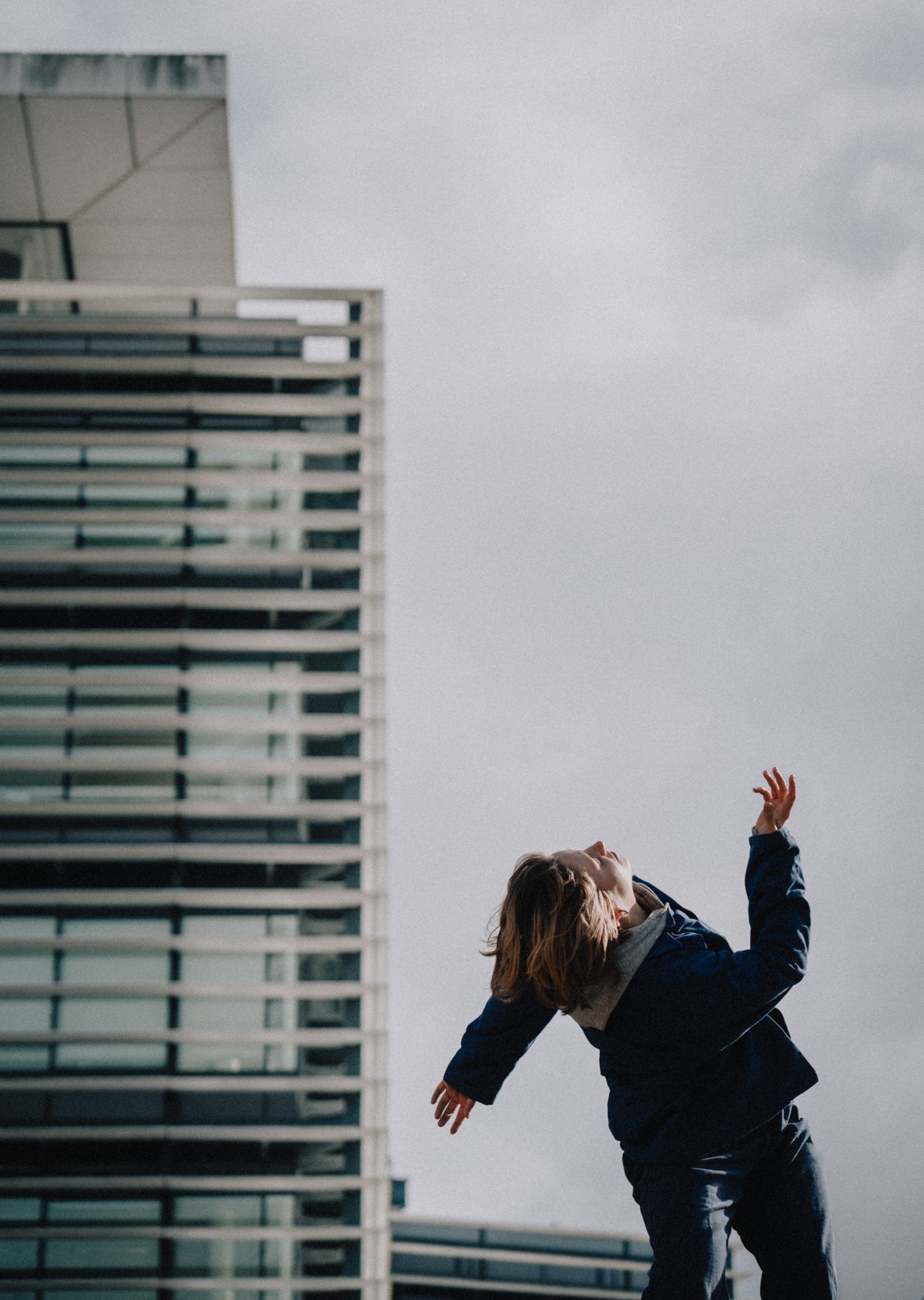 Photo artistique d’une danseuse en mouvement devant un immeuble moderne à Bordeaux, style urbain contemporain.